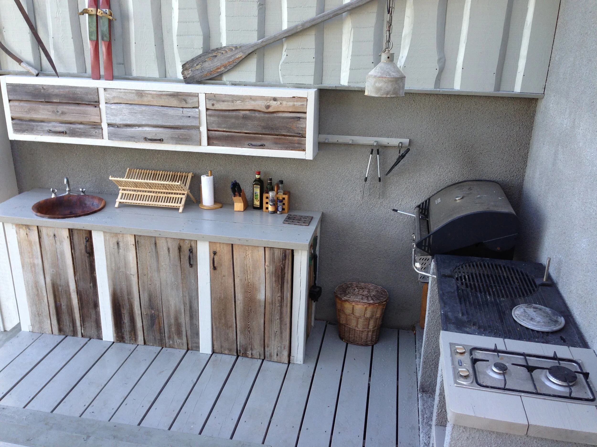 Kesäkeittiö kaikilla varusteilla, puusepän tekemien ovien takana on integroitu jääkaappi