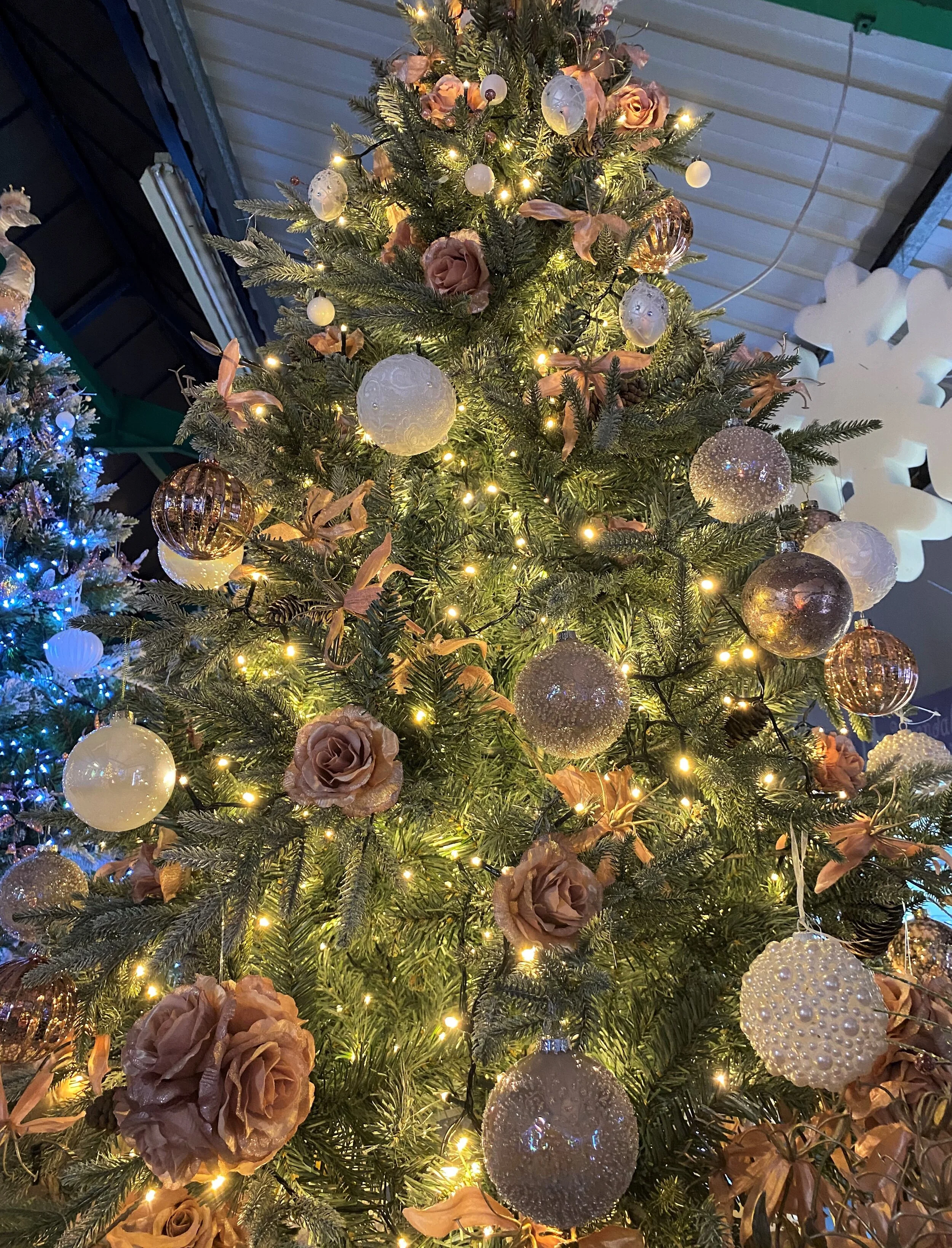 Decorated Christmas tree with gold and white ornaments, pink roses, and warm white lights.