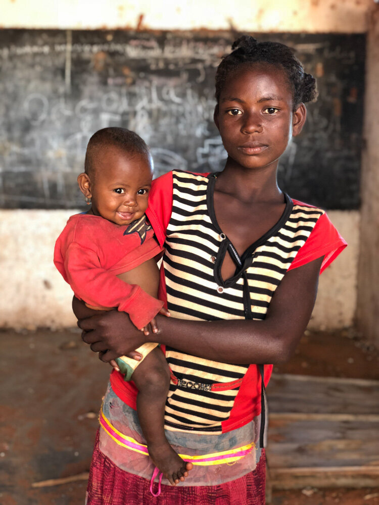  Une jeune fille porte un enfant dans l'école du village. Le sud de Magagascar souffre de la sécheresse chronique. Avec Caritas France. Ambovombe, Madagascar. Mai 2018 // A girl carries a child in the village school. The south of Magagascar suffers f