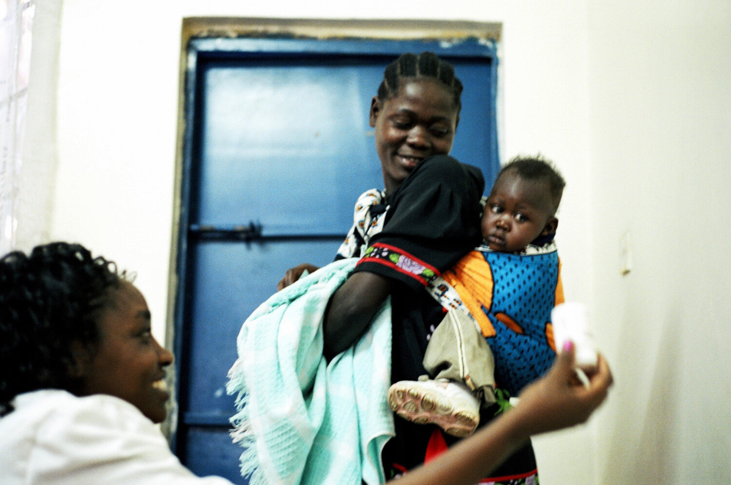  Une femme et son enfant se font délivrer par une infirmière les médicaments ARV, dans la clinique SIDA du bidonville de Matharé. Avec Médecins Sans Frontières, dans la lutte pour l'accès aux médicaments essentiels. Nairobi, Kenya. Mars 2005 // A wom