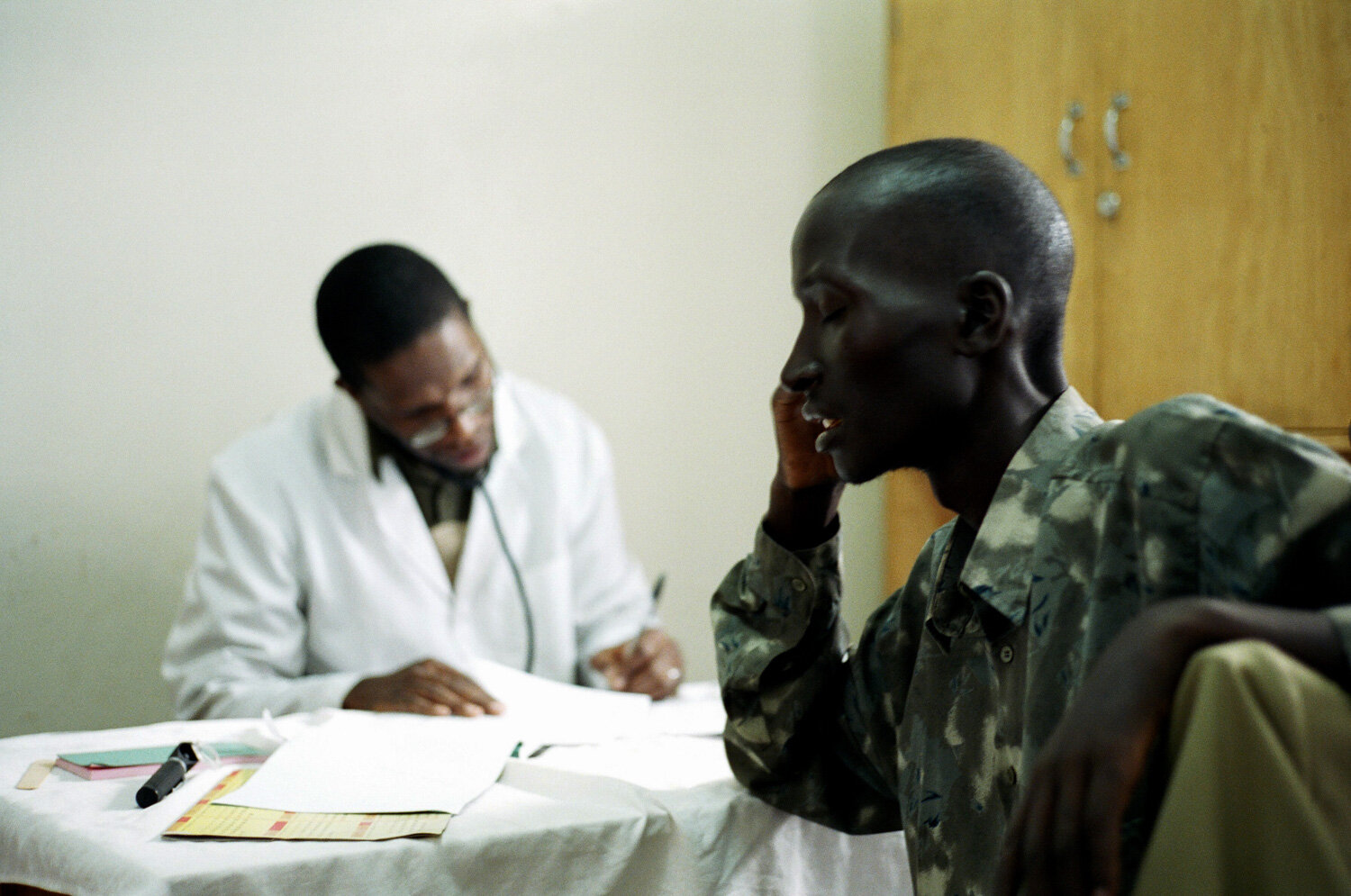  Un médecin fait une presciption au mari après lui avoir annoncé sa maladie, dans la clinique SIDA du bidonville de Matharé. Avec Médecins Sans Frontières, dans la lutte pour l'accès aux médicaments essentiels. Nairobi, Kenya. Mars 2005 // A doctor p