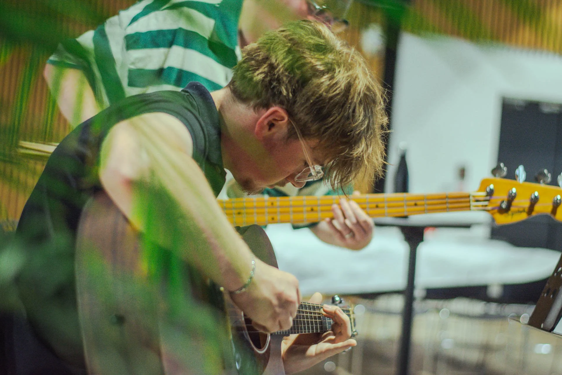 Group of young adults playing guitars together in a music practice room.