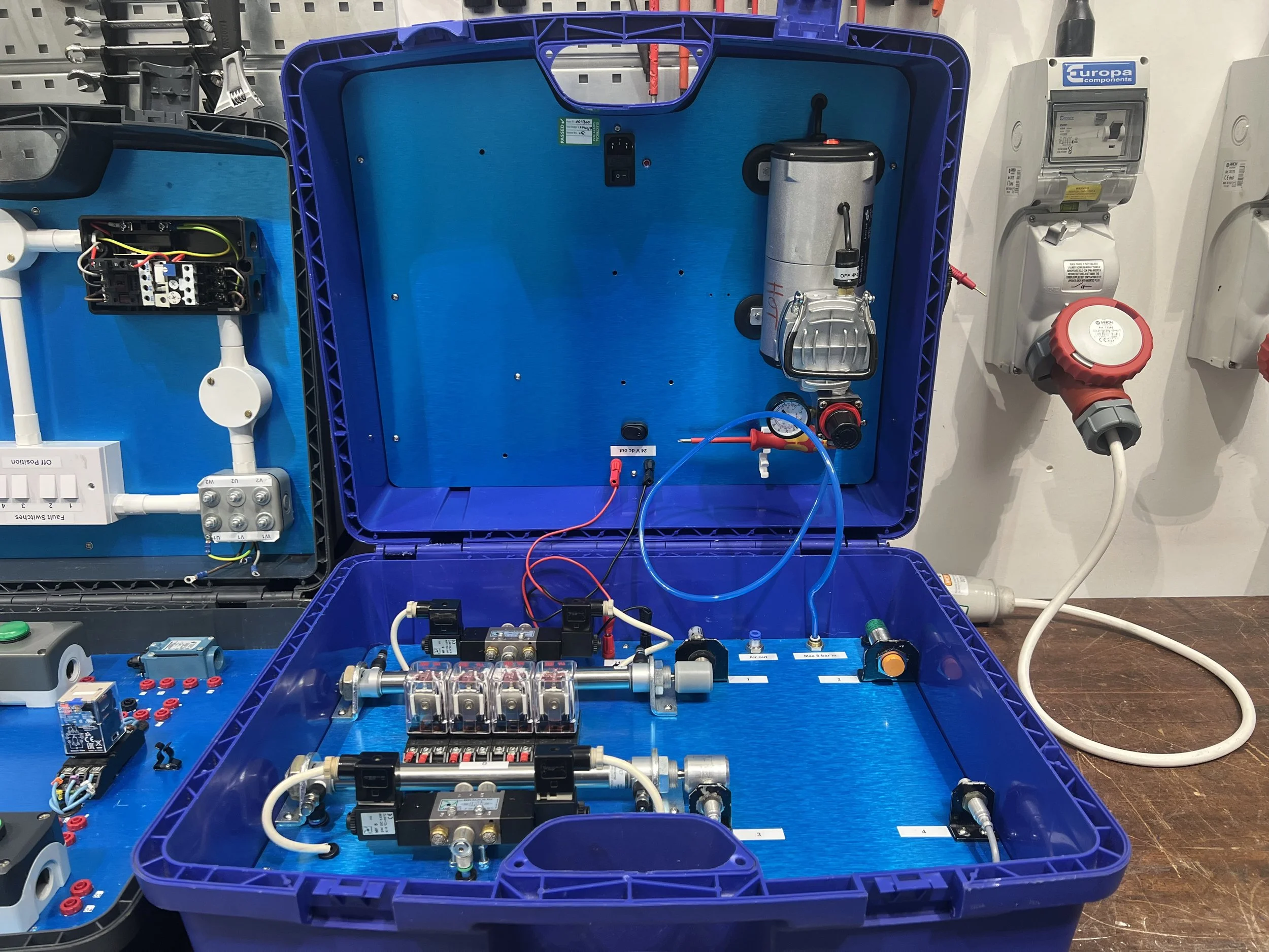 An open blue plastic case containing various electronic components, tubing, and wires, with parts mounted on the interior walls and base, likely a scientific or industrial device.