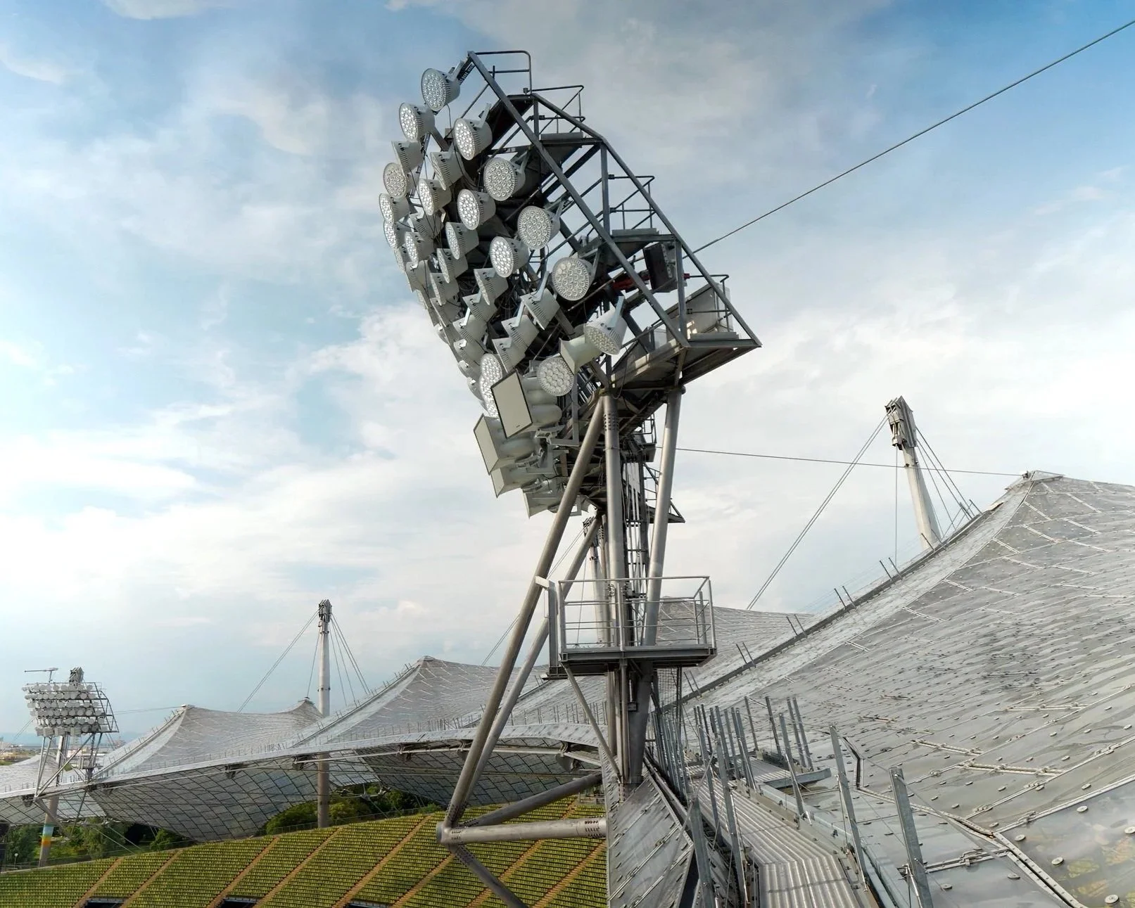 Große Veranstaltungsbühne mit mehreren Scheinwerfern und Solarpaneelen auf einem Dach, im Hintergrund ein blauer Himmel mit Wolken.