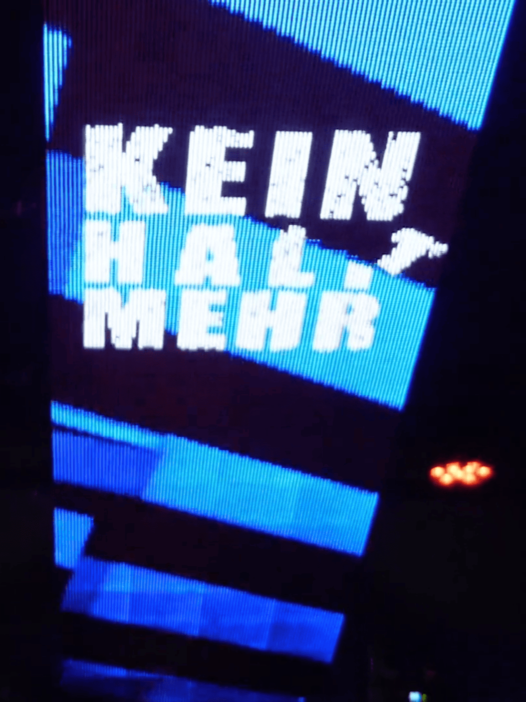 Lichtanzeige mit dem Text "Kreis Hall Mehrb" in einem dunklen Raum, umgeben von roten Lichtquellen.