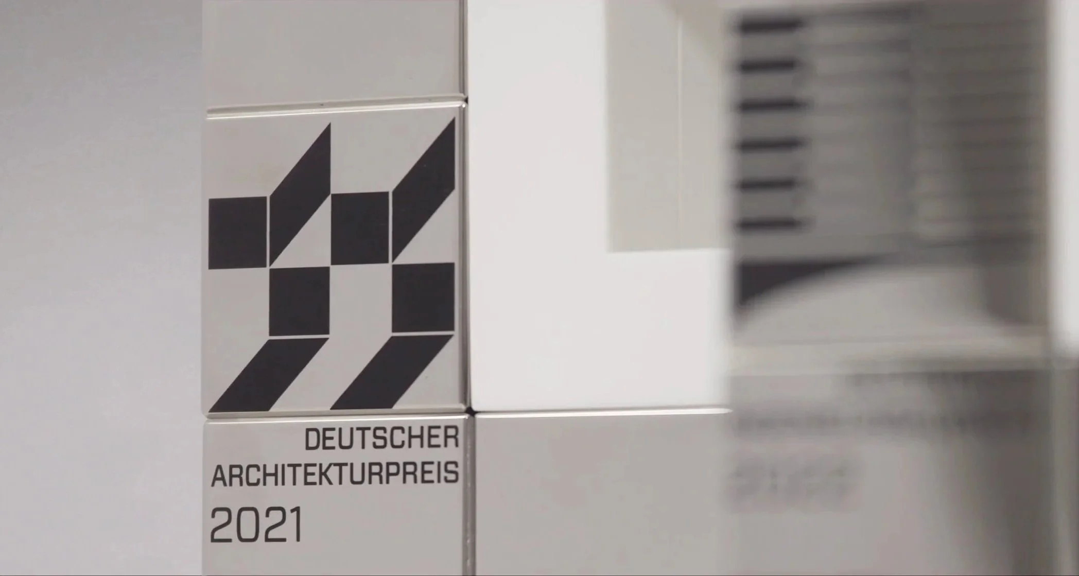 metallene Plakette des Deutschen Architekturpreises 2021 mit schwarzem geometrischem Design