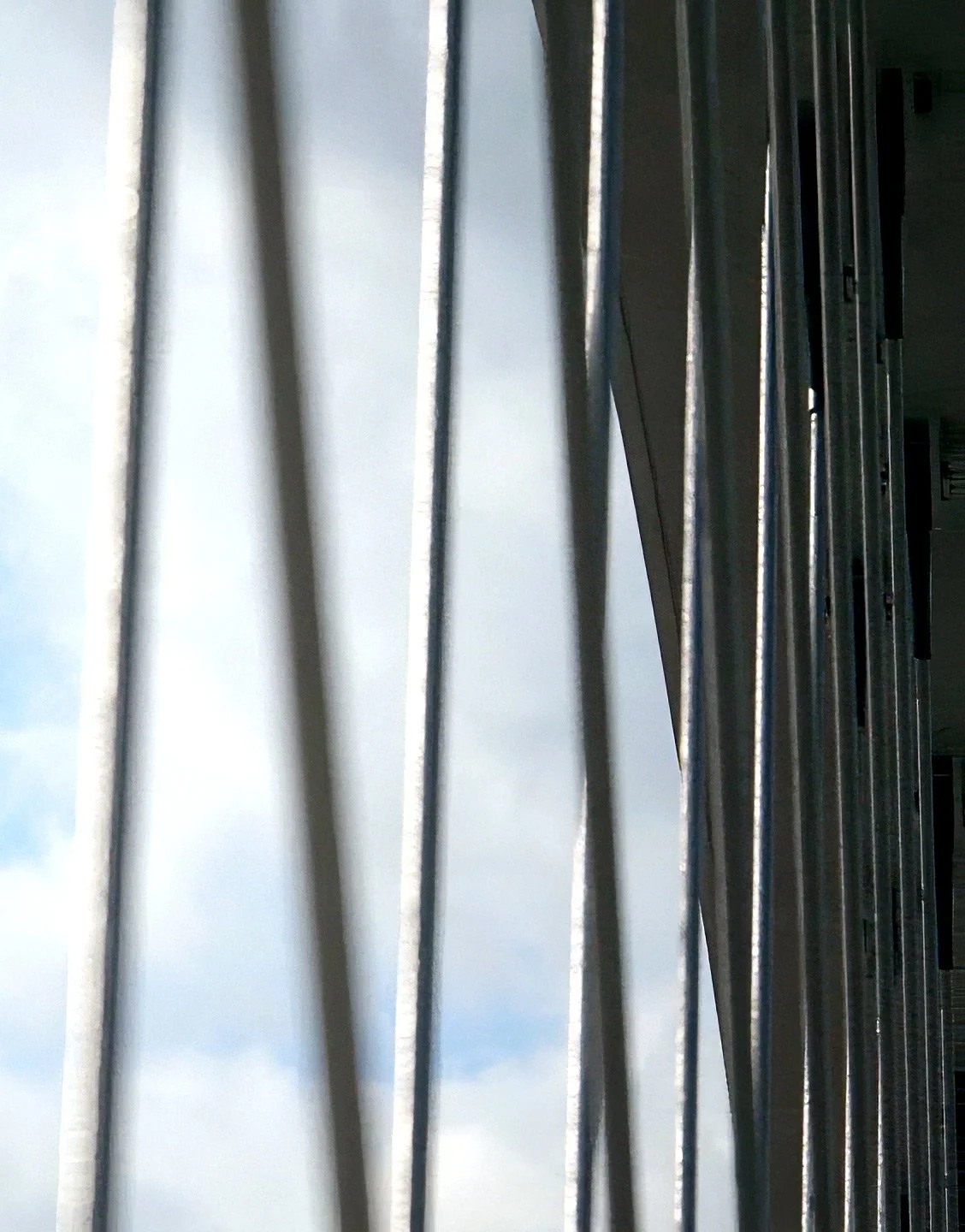 Blick durch die Metallstäbe eines Gitters mit Himmel im Hintergrund.