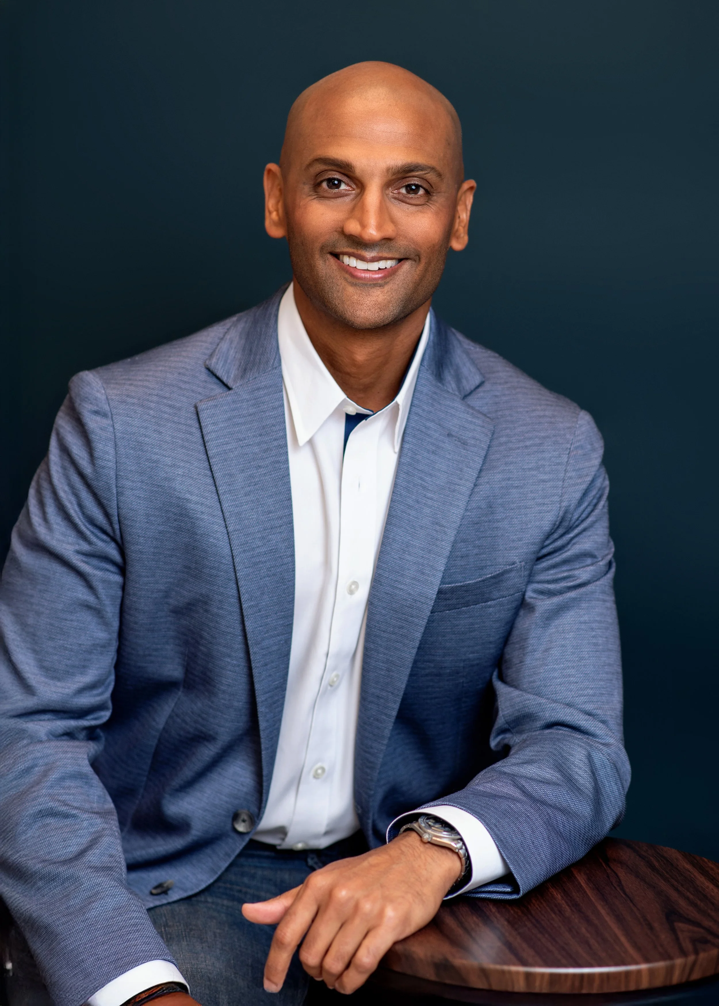 Man on a dark blue background posing for headshots in Houston.