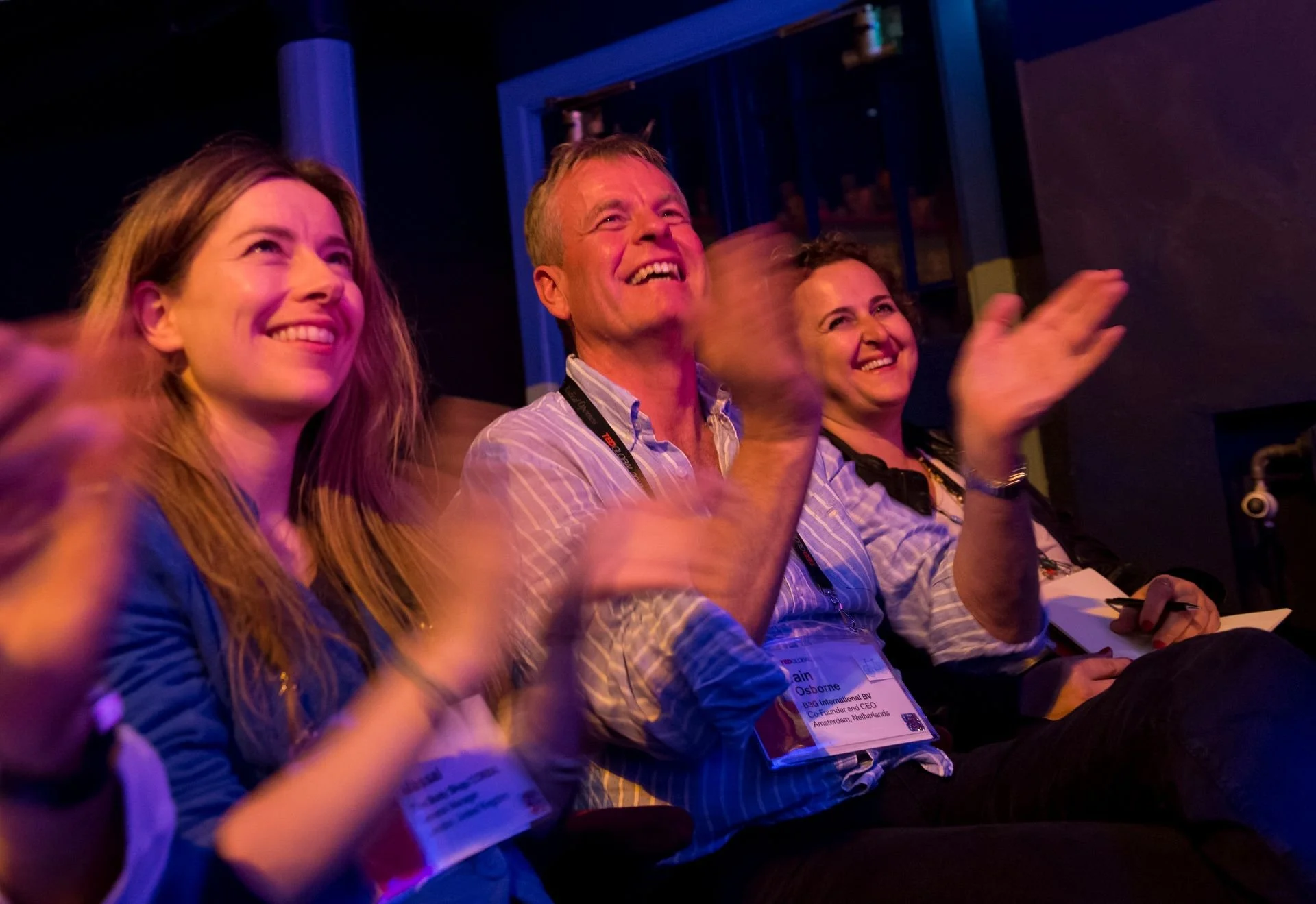Audience members smiling and applauding during a scientific presentation.