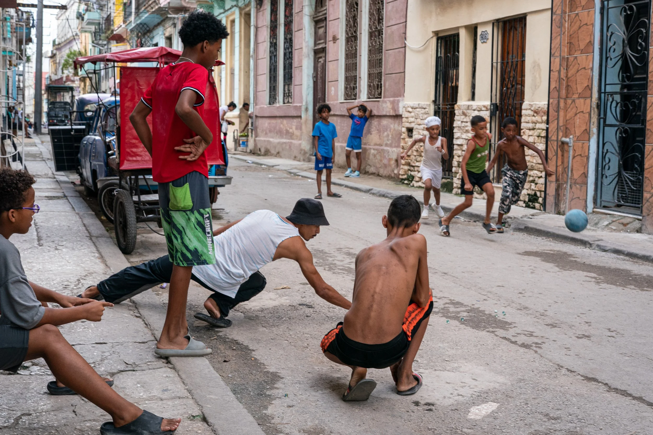Boys playing marbles and footbal in the street in Havana, Cuba