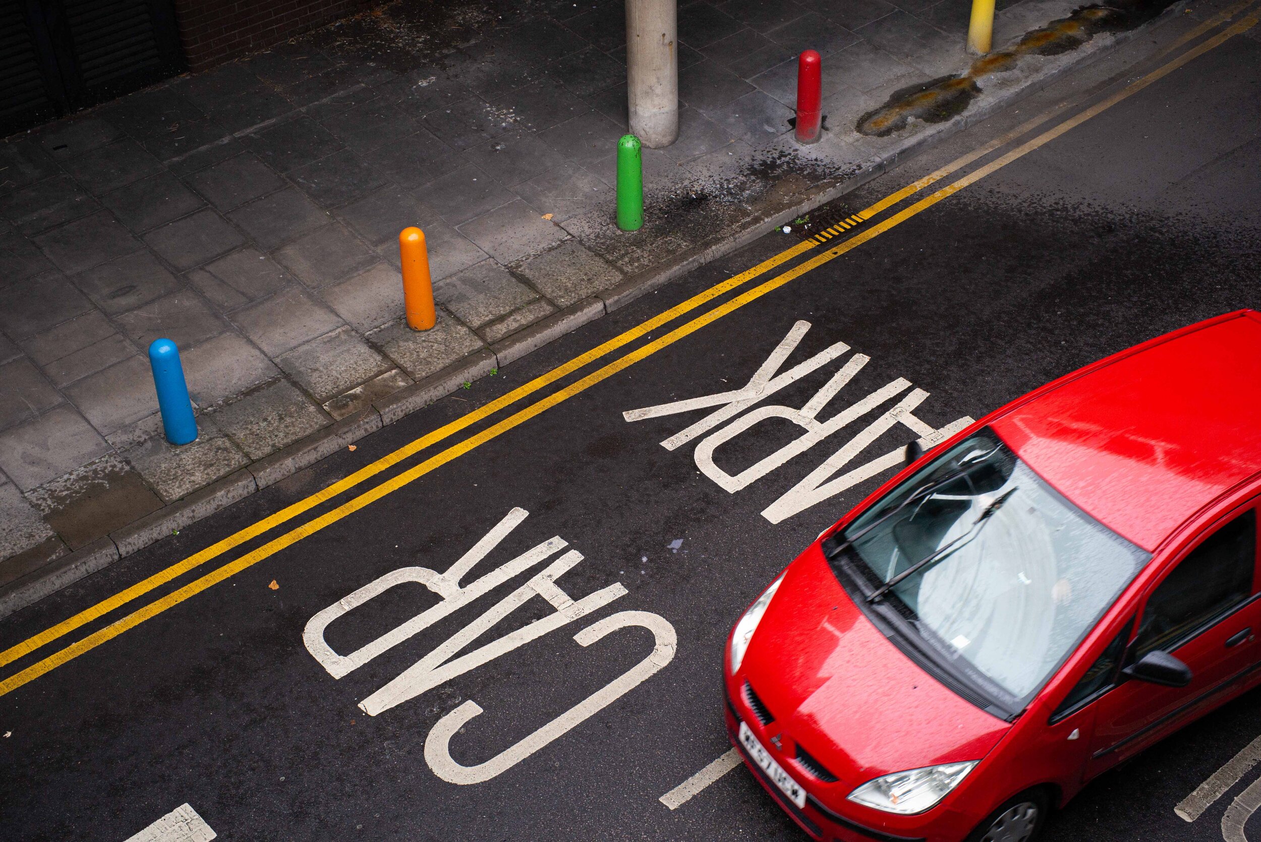 Colourful bollards and red car