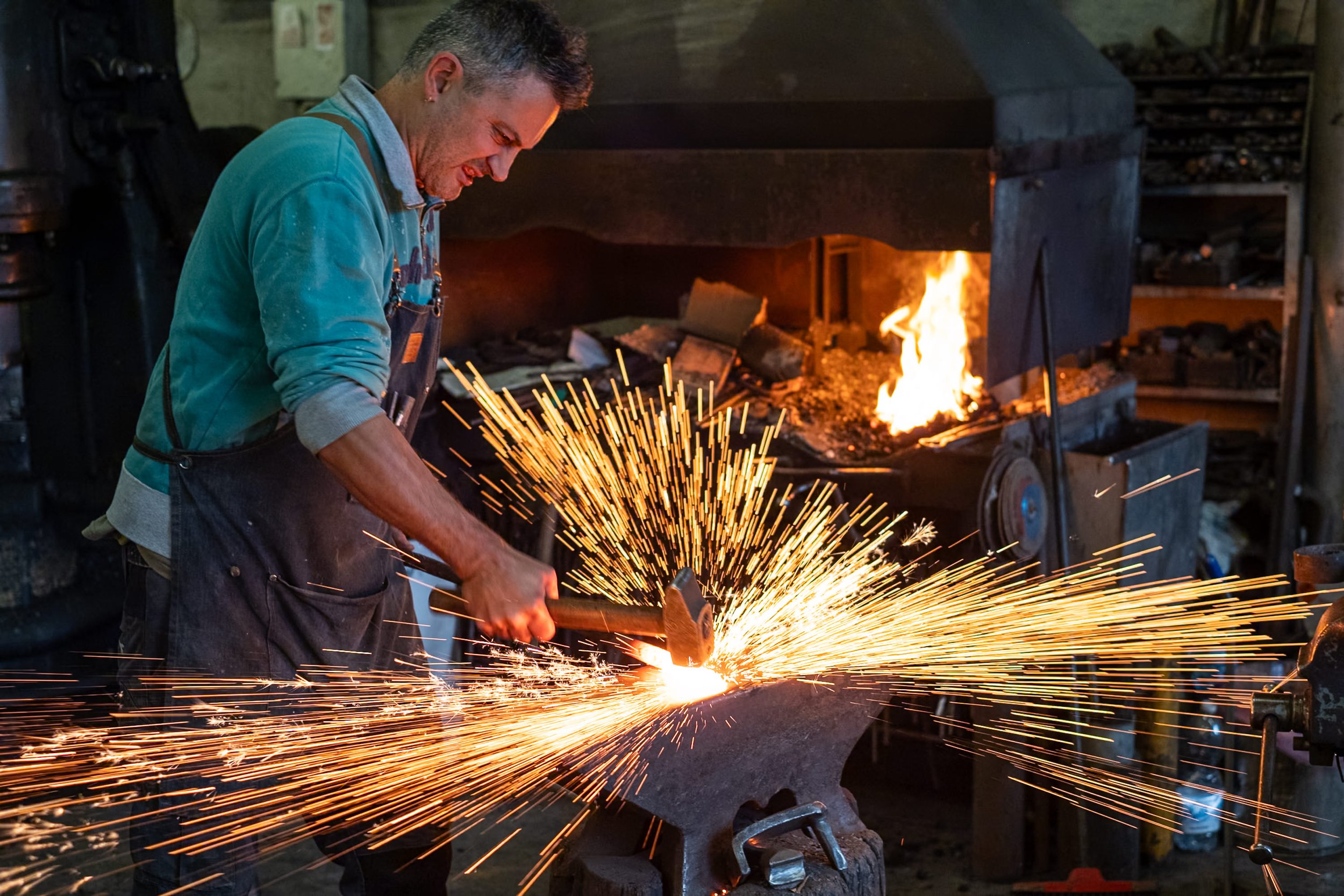 Blacksmith striking hot metal and spraying sparks in Canale d'Alba, Italy