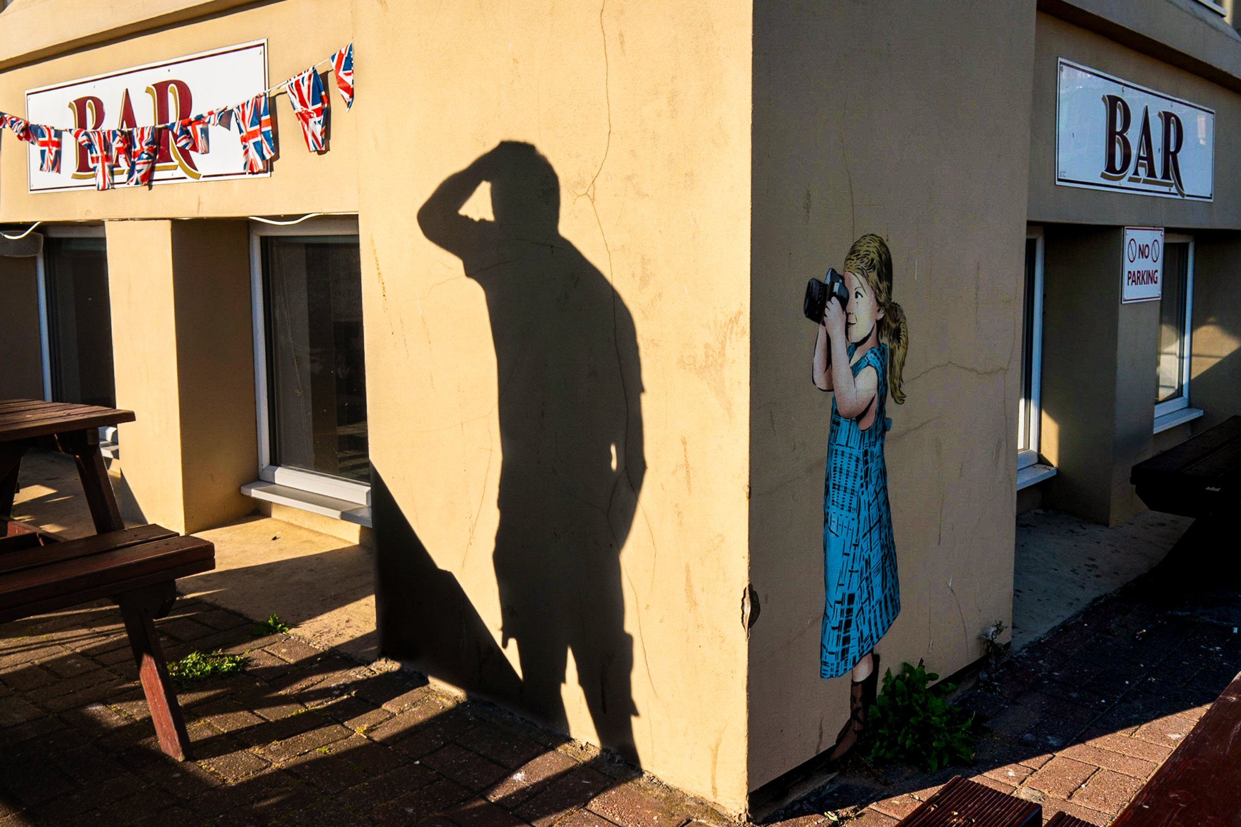 Graffiti girl taking photograph of shadow on wall