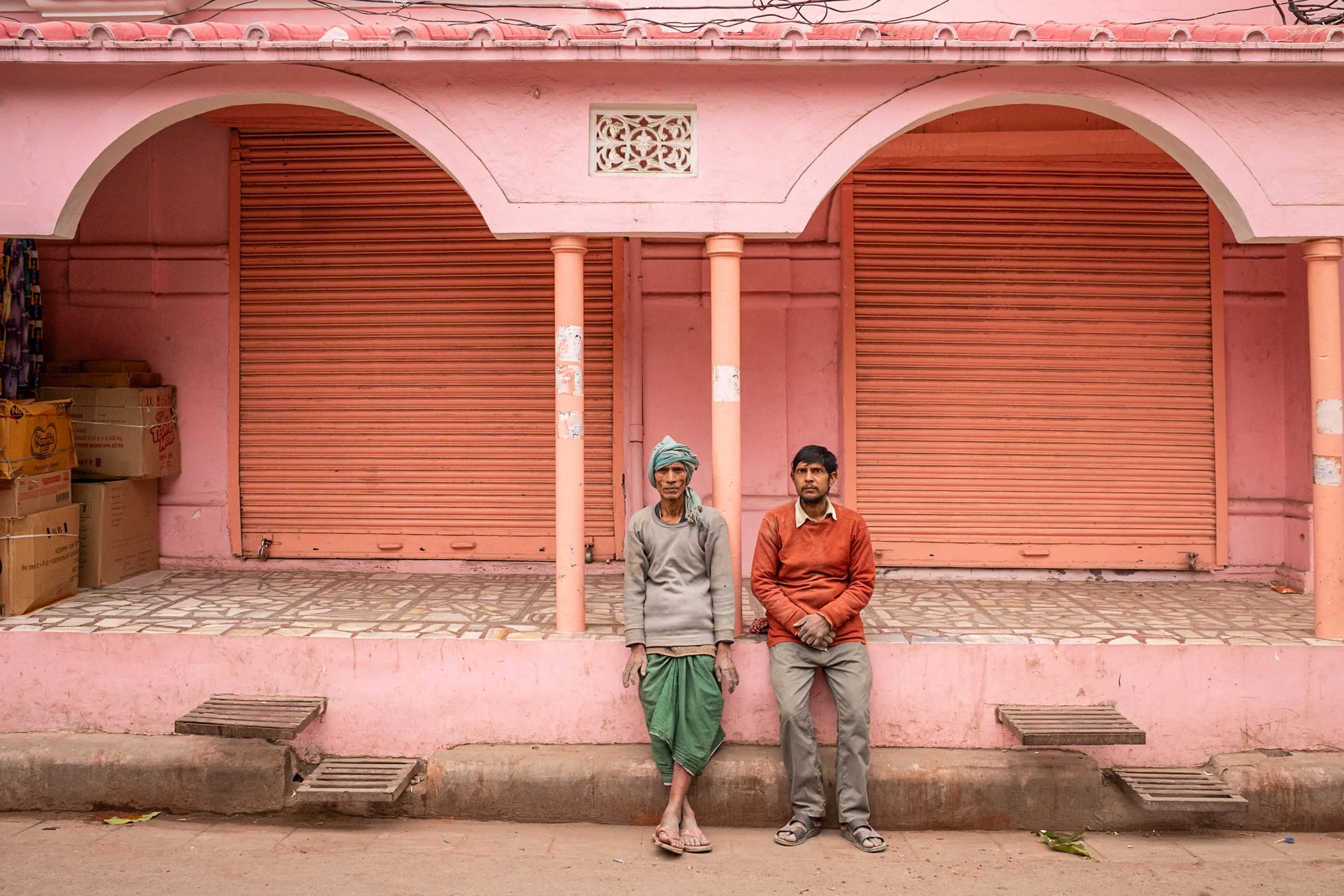 Two men in front of pink building in Varanasi