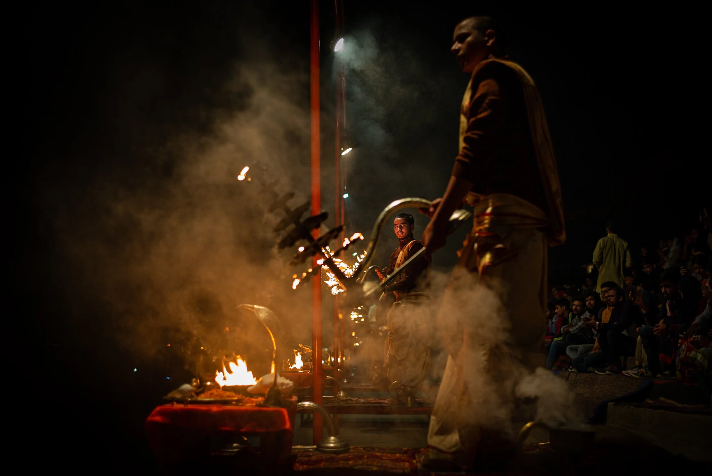 Young monk framed by chandelier in Aarti ceremony in Varanasi