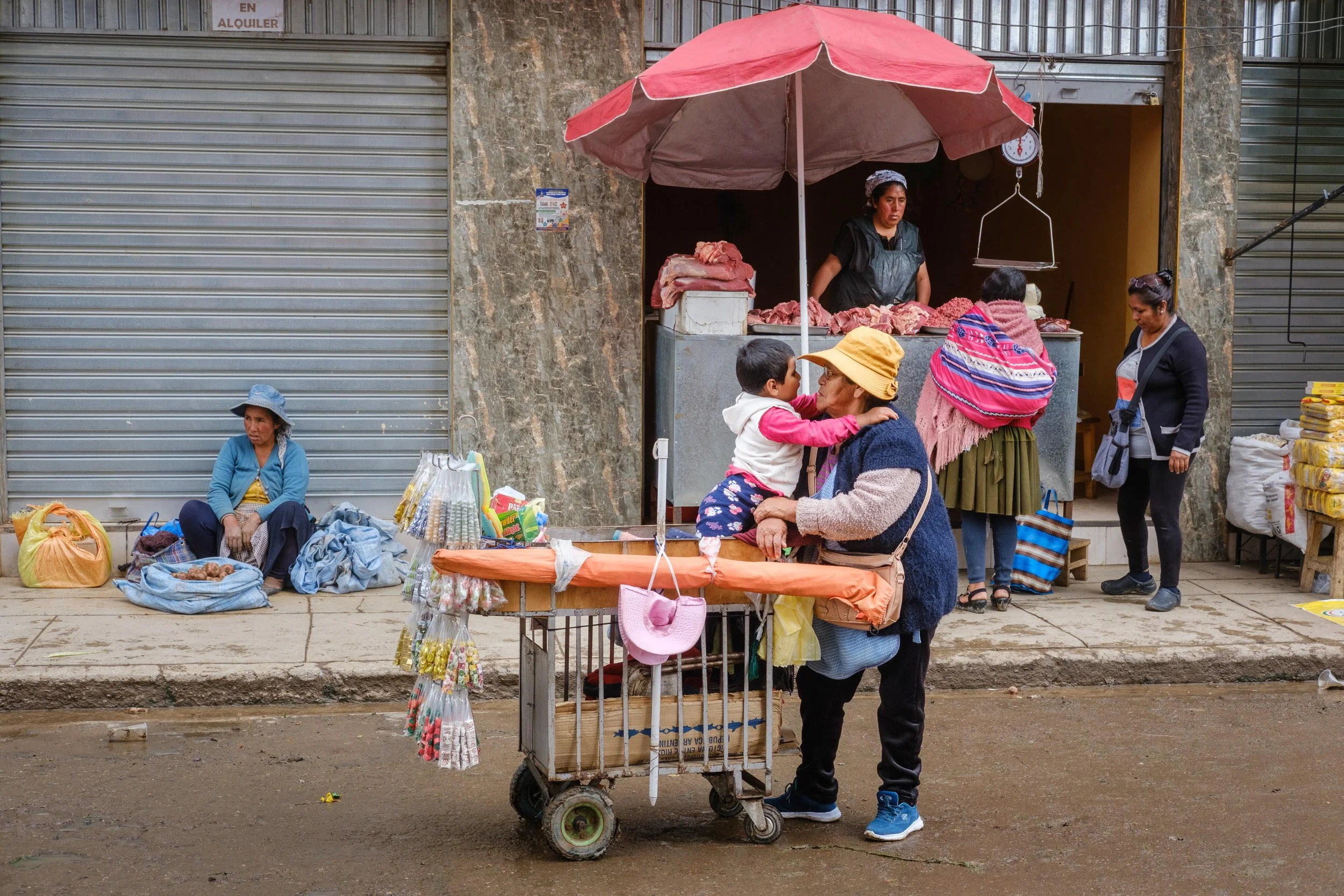 Street hawker woman with grandchild on cart in Triangulo market in Cochabamba