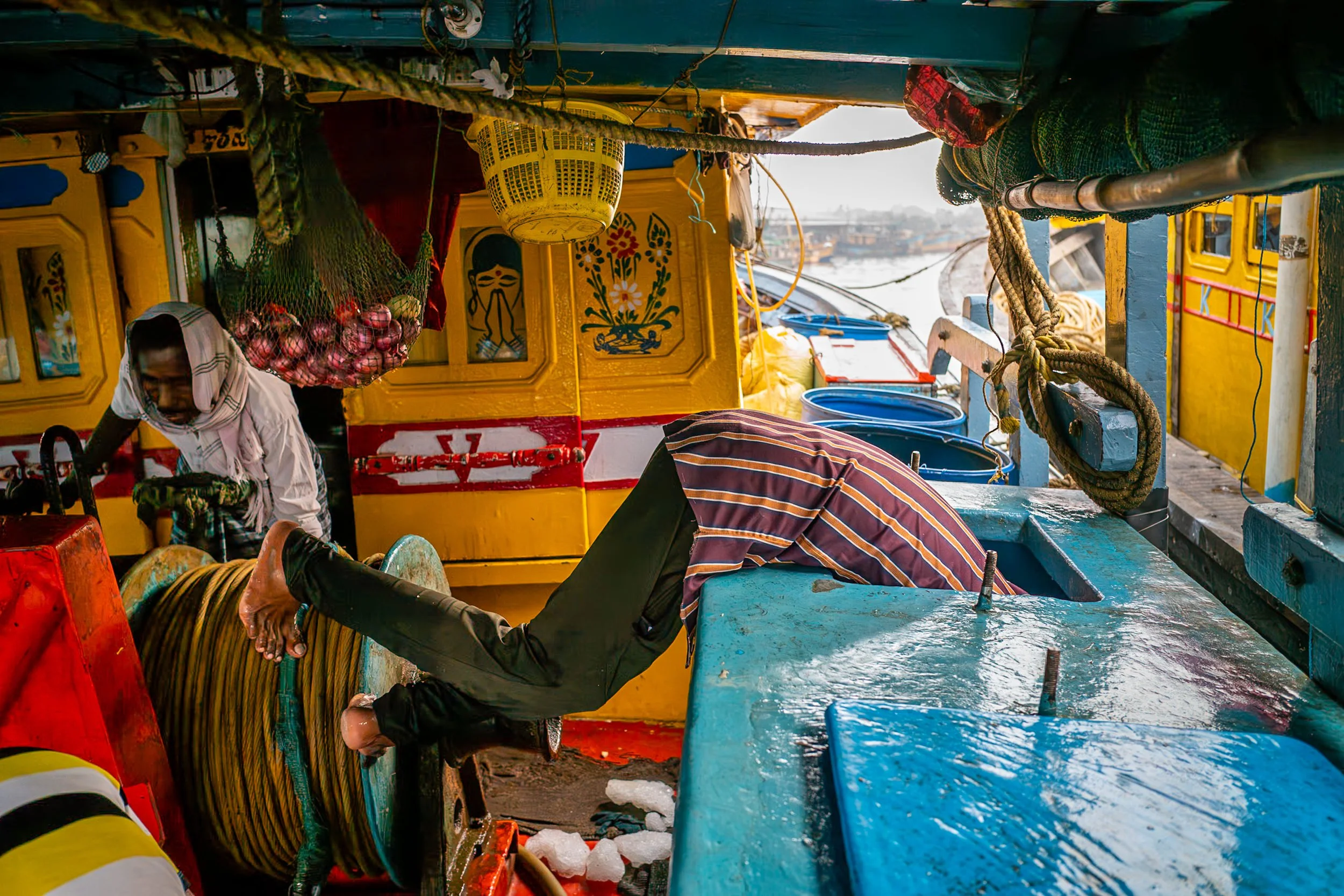 Fisherman reaching into storage on boat in Visakhapatnam fish market