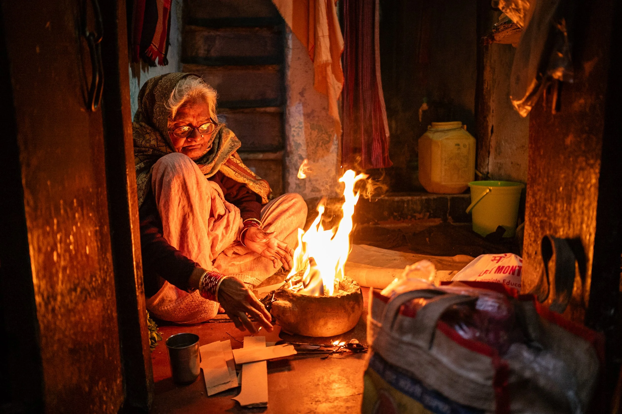 Portrait of elderly woman warming up with fire in Varanasi