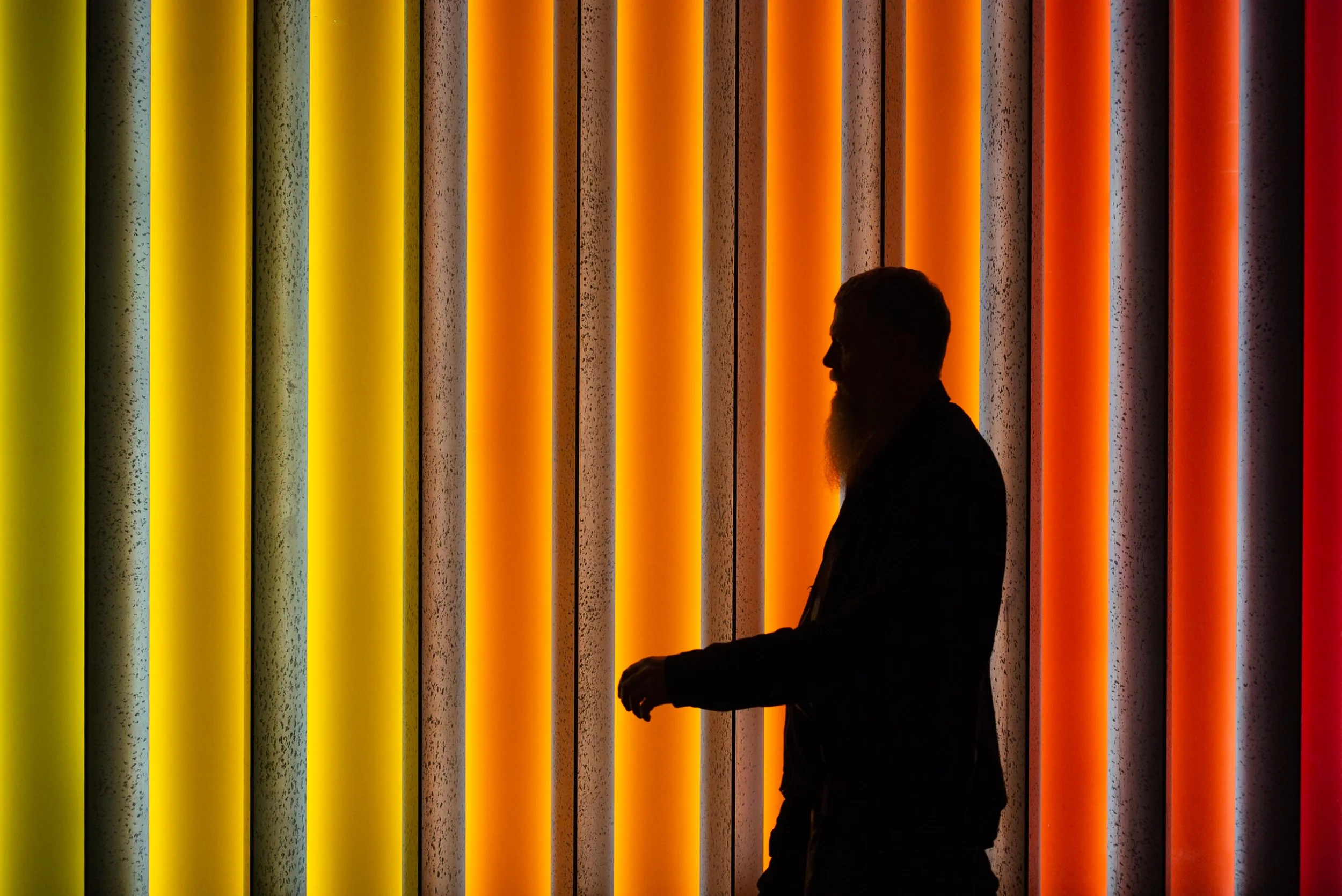 Silhouetted man walking on colourful background
