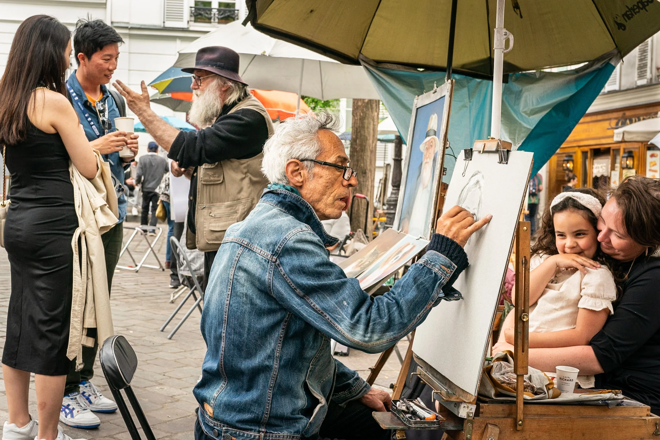 Street artist making portrait of little girl in Paris