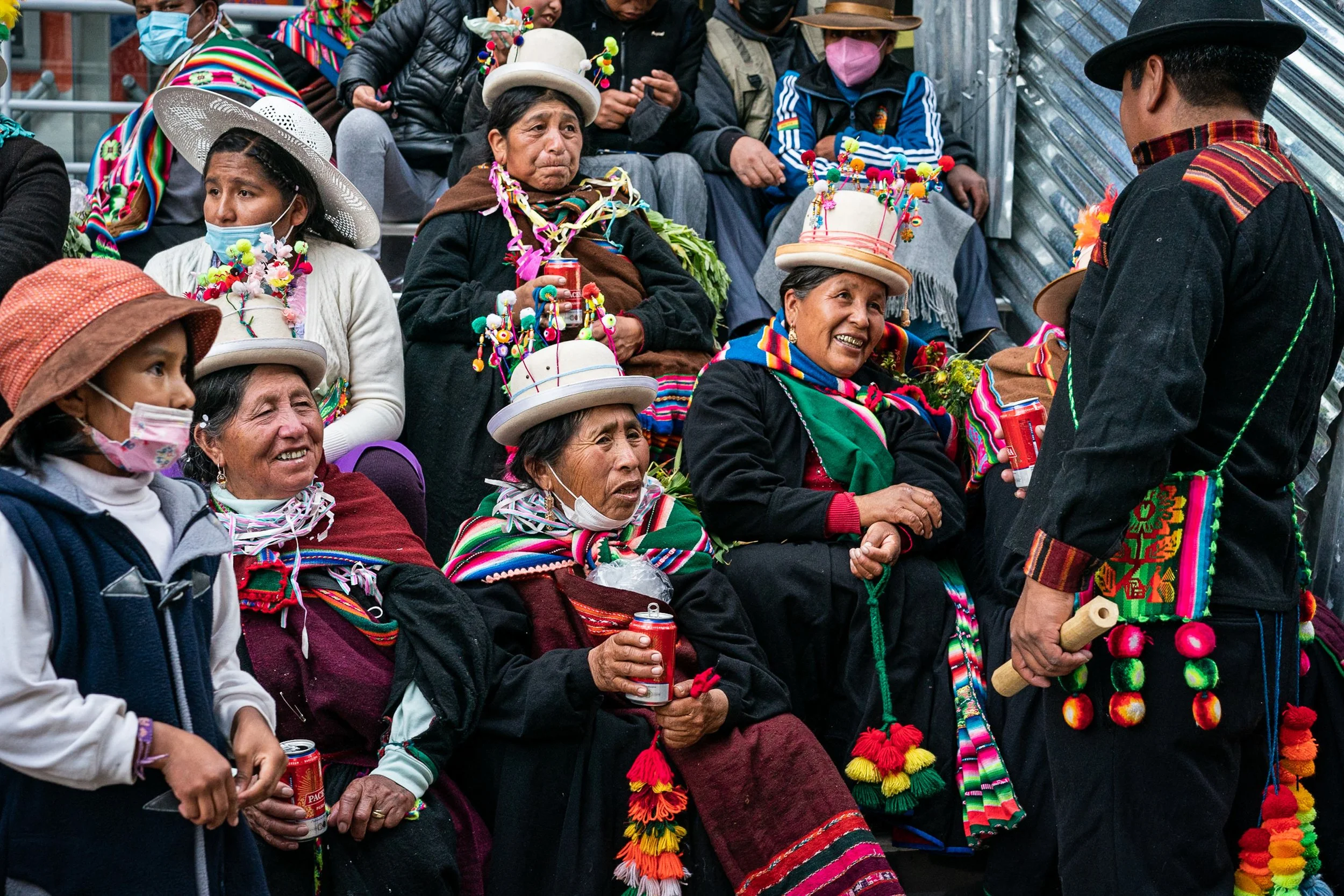 Group of cholitas sitting together talking to man in Oruro