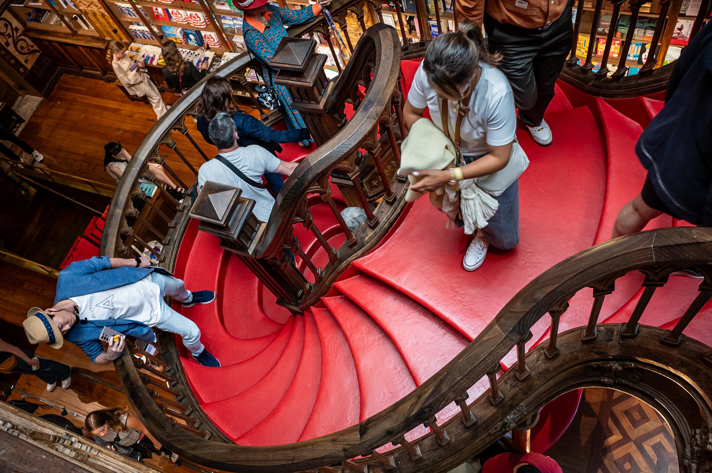 Man hangin off staircase in Livraria Lello in Porto