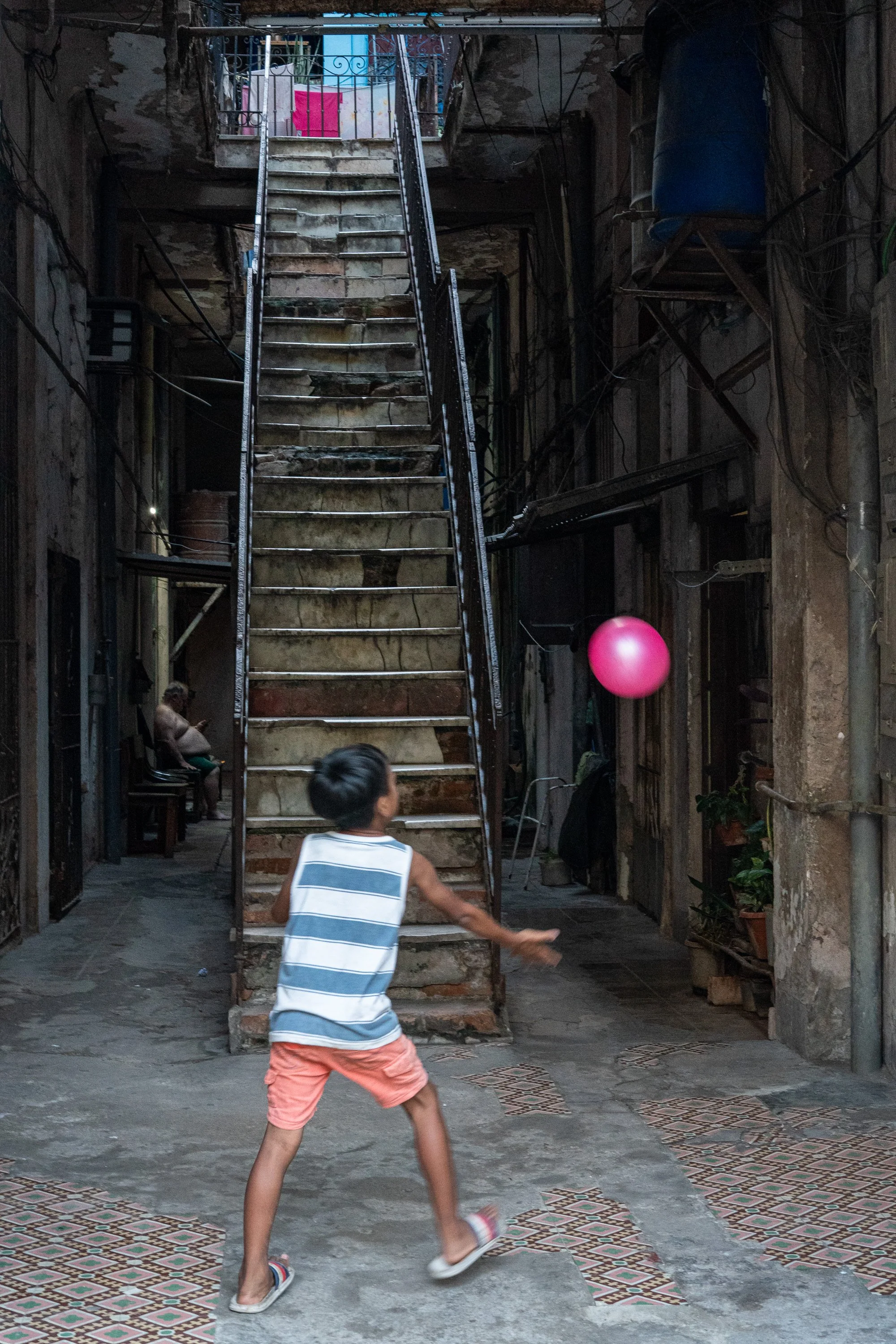 Boy playing with pink ball in front of staircase, Havana, Cuba