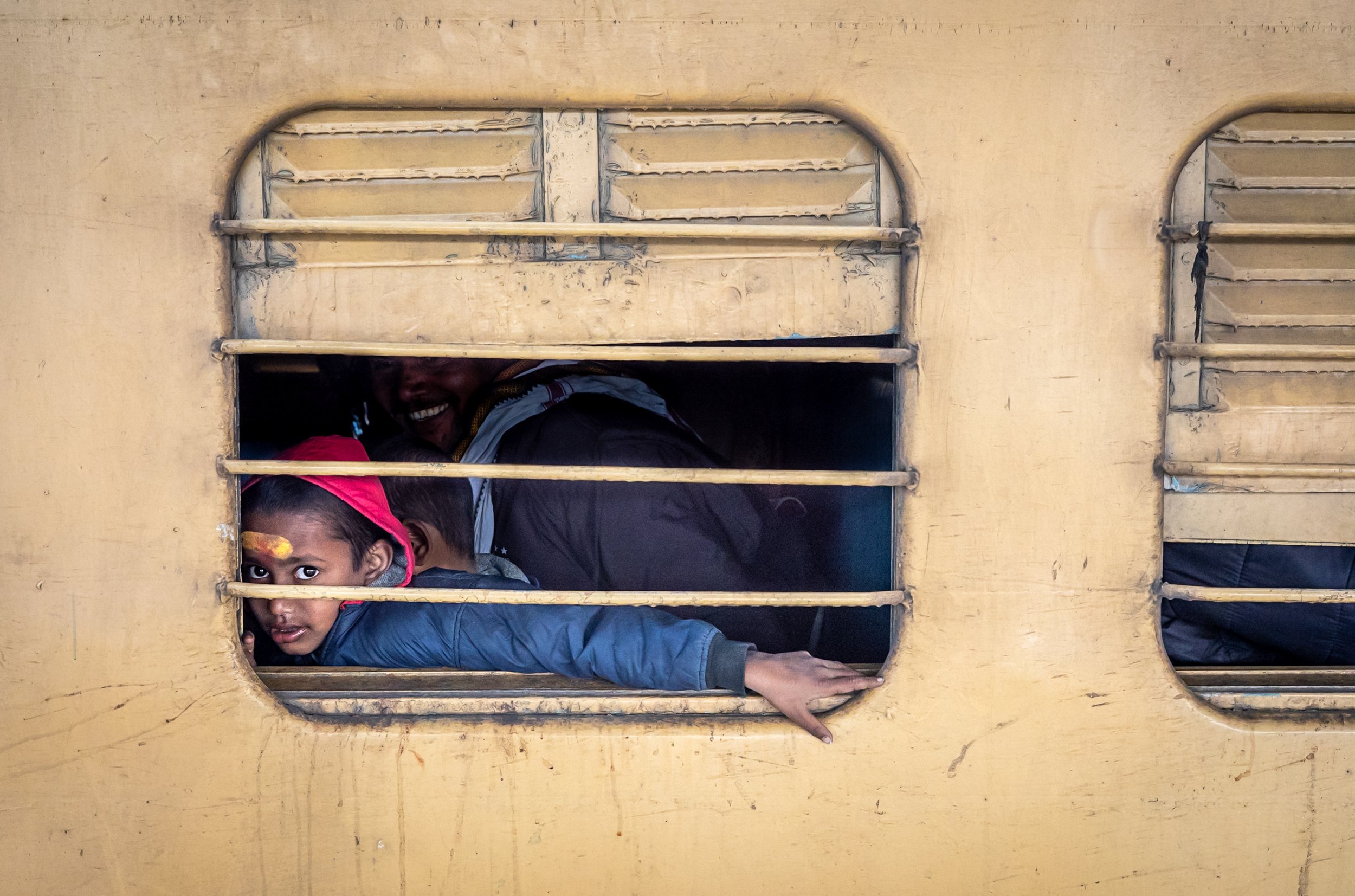 Portrait of child behind bars of train window in Allahabad