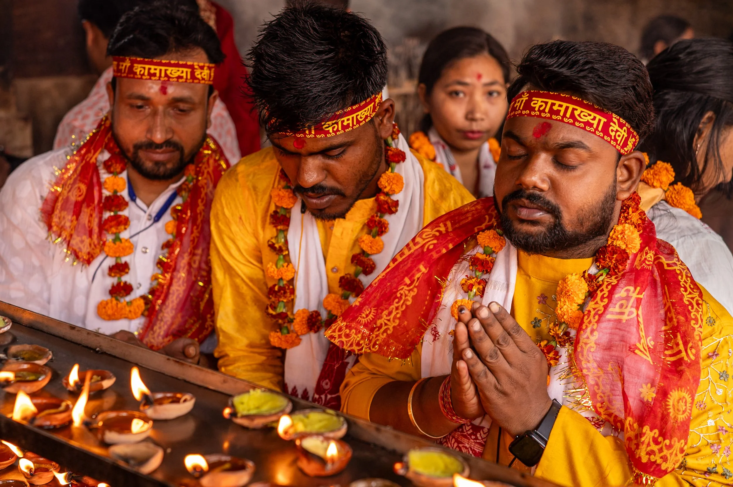 Devotees in yellow lighting offerings and praying in Guwahati Kamakhaya temple