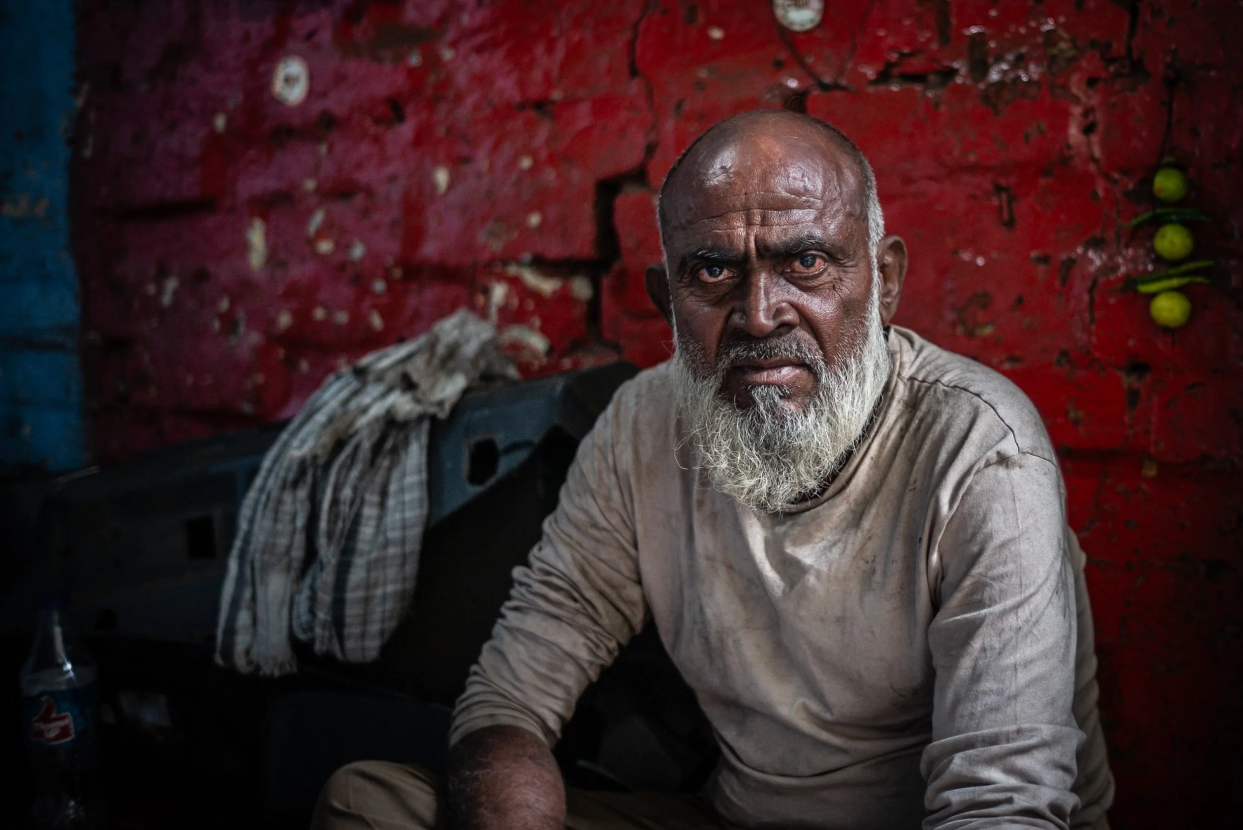 Portrait of labourer with intense eyes on red background in Kolkata