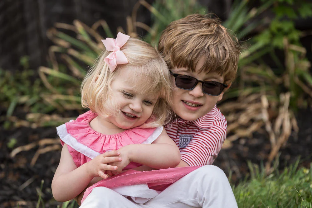 young boy hugs his little sister