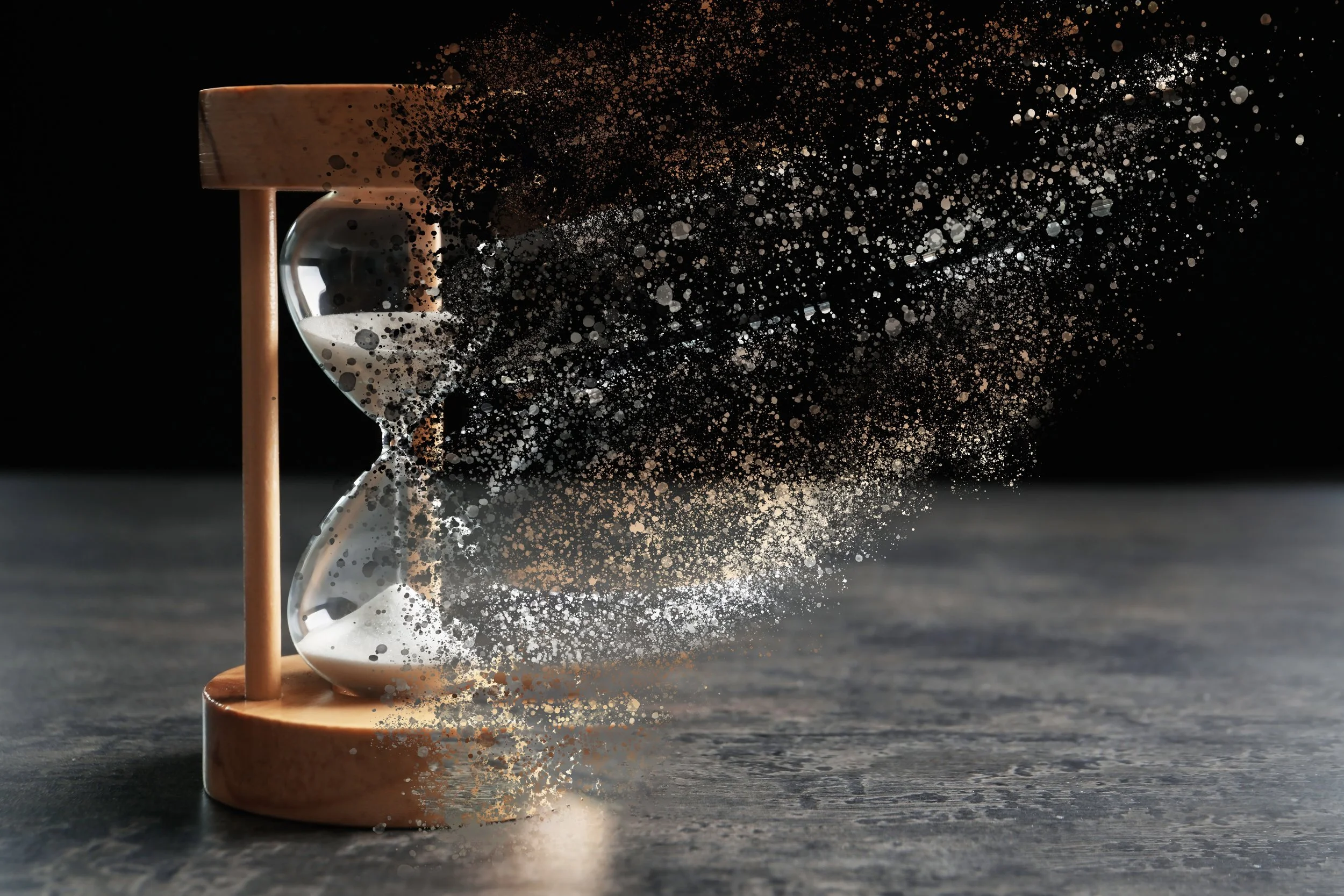 Sand hourglass with disintegrating particles flying off to the right
