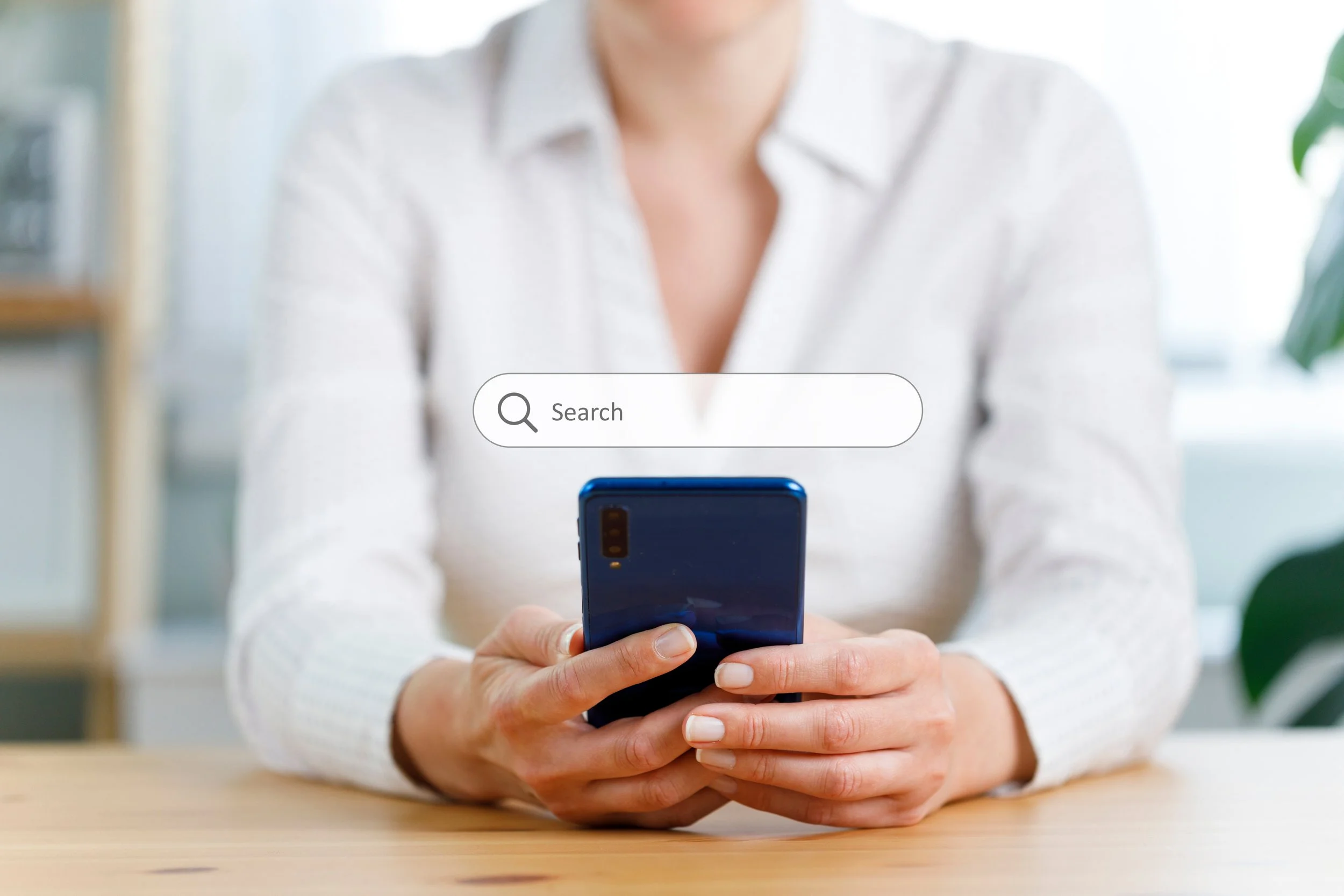A woman holding a phone with a hovering search bar above it