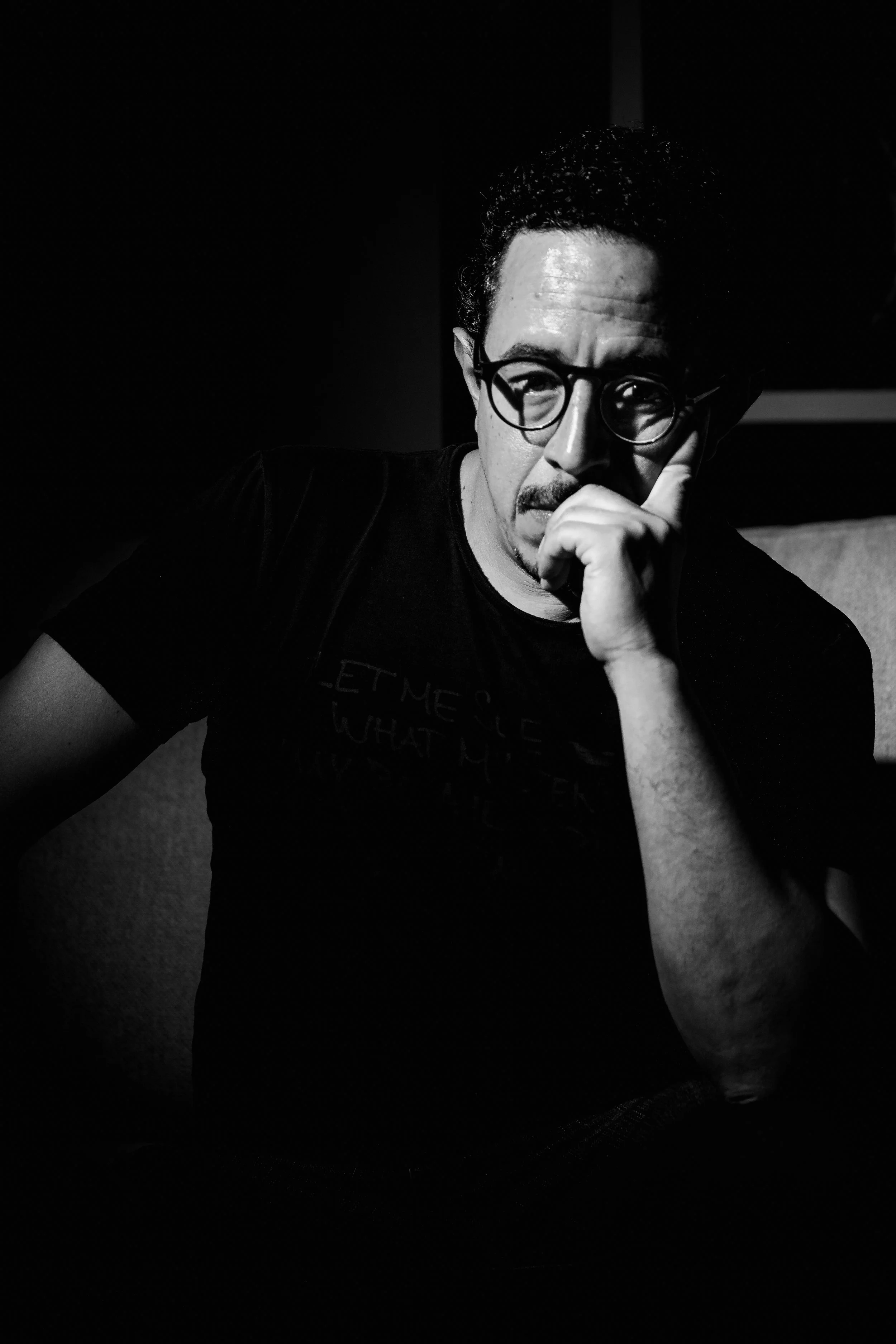 Autorretrato de Rodrigo Ojeda en blanco y negro, pensativo, en luz tenue.