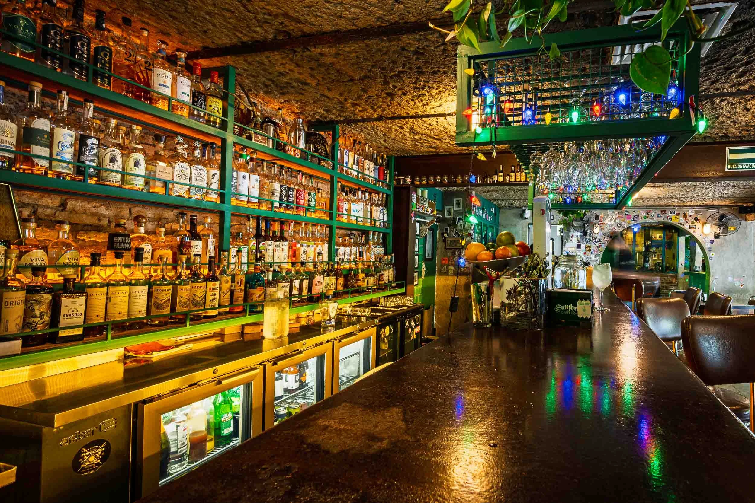 Barra colorida con cientos de botellas de mezcal y tequila en La Farmacia Rita Perez, escena ideal para editorial de viajes o reportaje cultural.