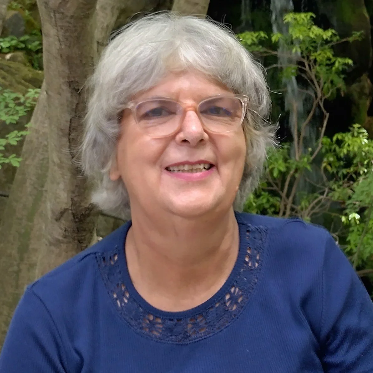 portrait of white haired lady against background of trees