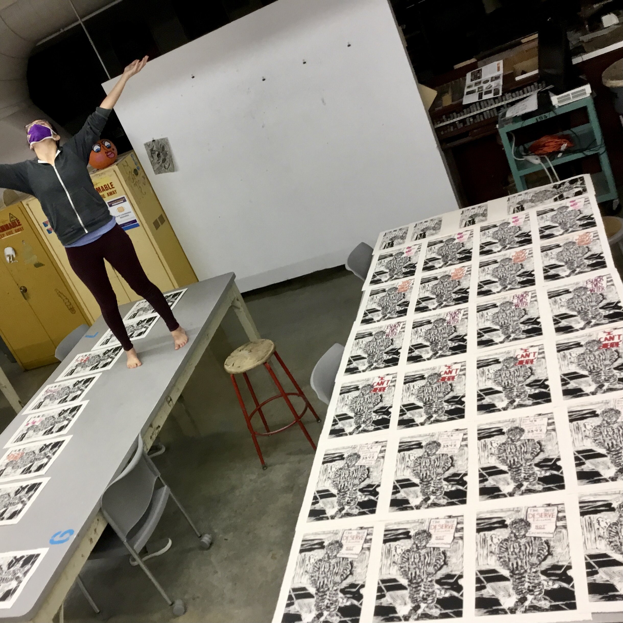 Alissa standing on a table showing off a series of prints