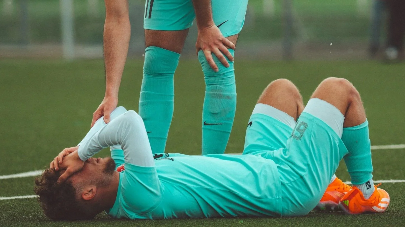 Soccer player lying on the ground after a muscle strain injury during sport