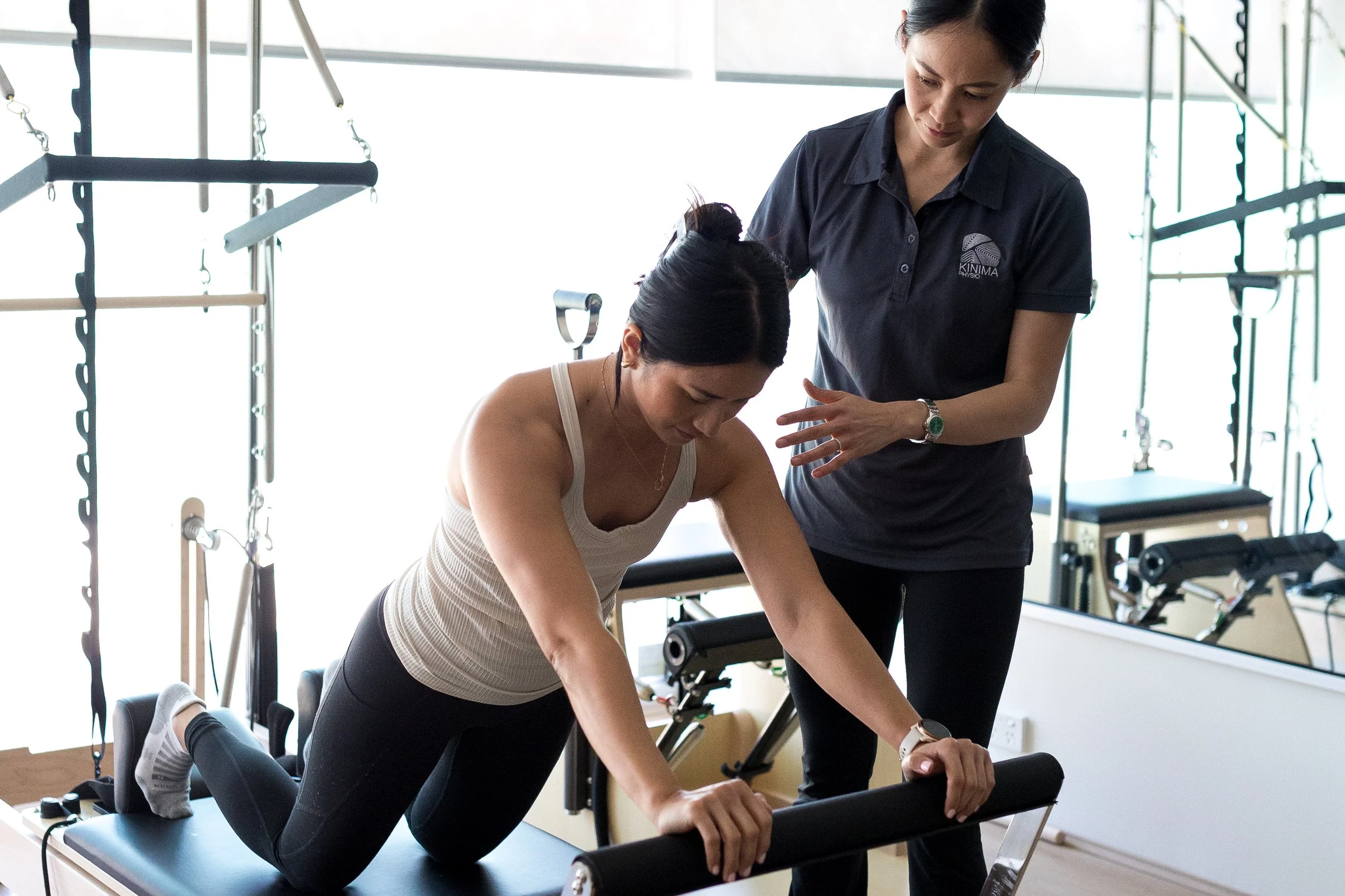 Physiotherapist guiding a client through a Clinical Pilates exercise during a one on one physiotherapy session at Kinima Physio.