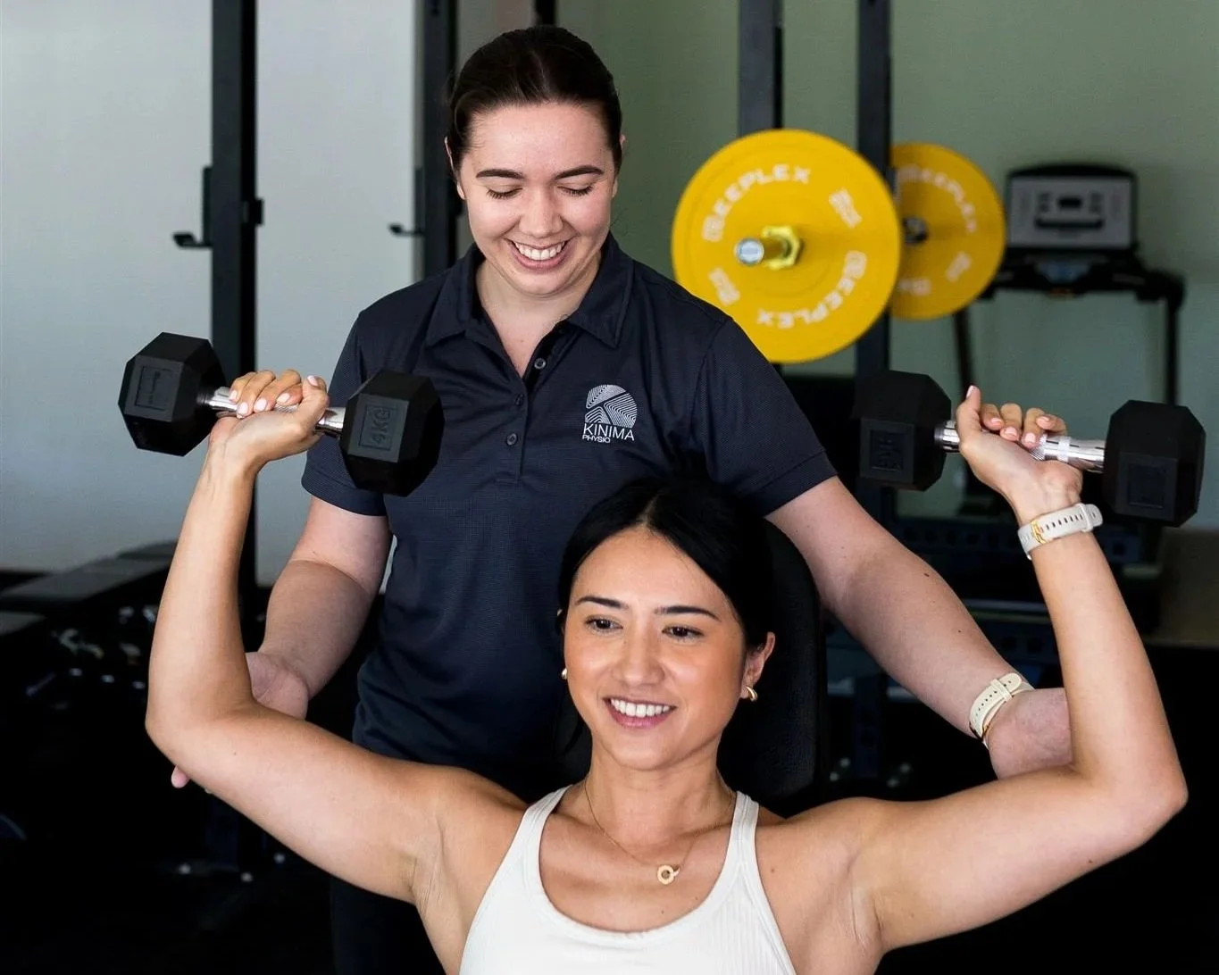A strong female client being supervised by a female physiotherapist through shoulder rehabilitation exercises