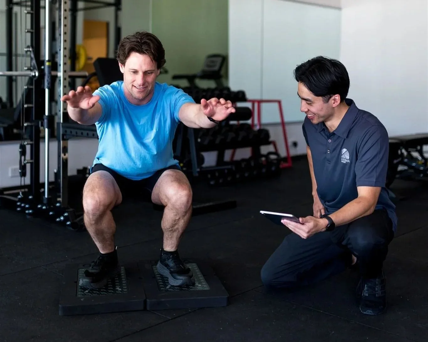Physiotherapist assessing movement and squat technique as part of an individual rehabilitation program.