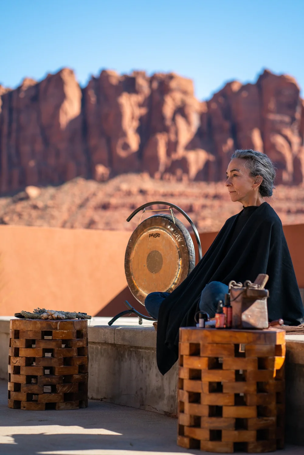 A woman playing a gong in the desert.