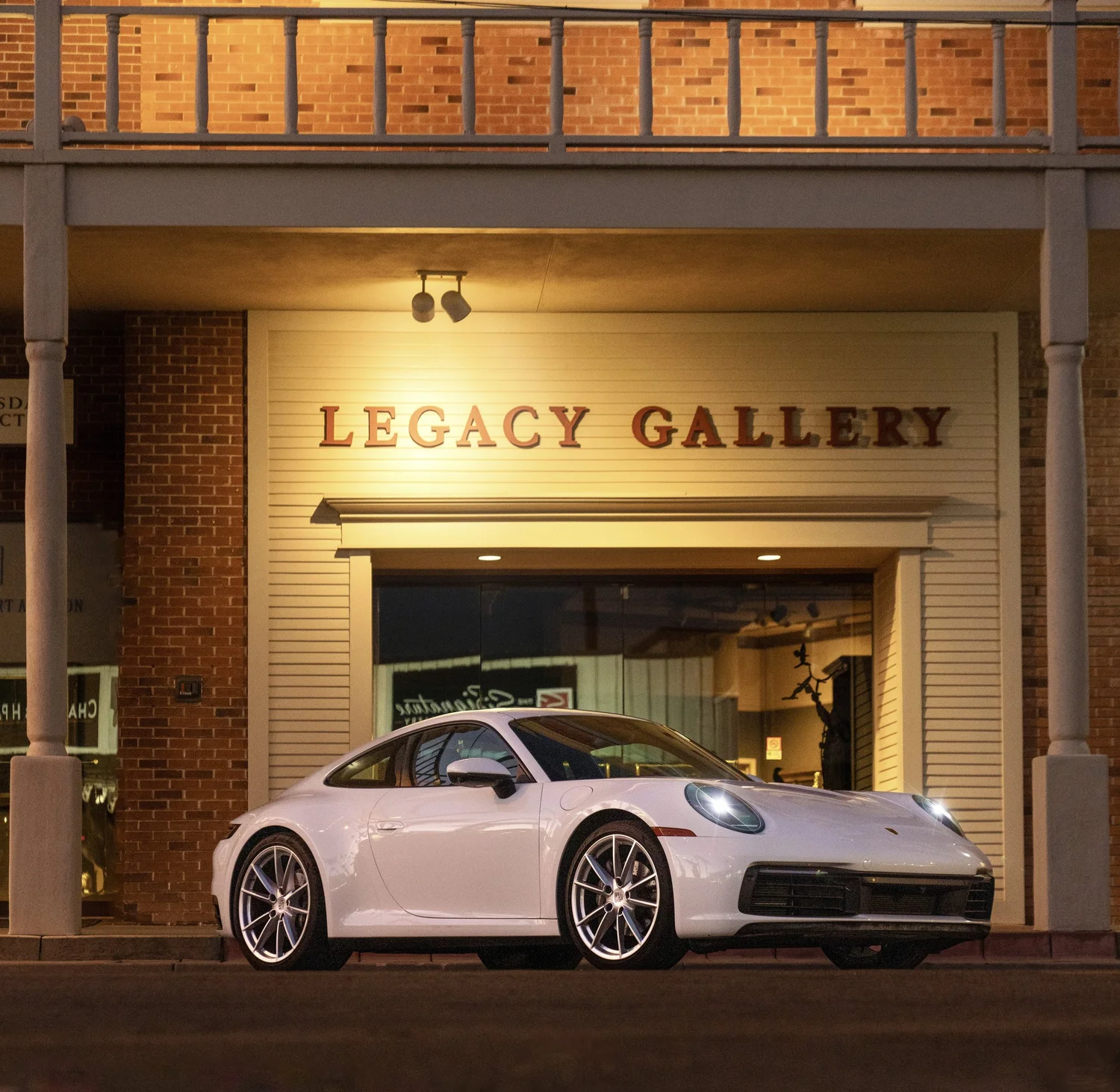 White Porsche photographed outside Legacy Gallery at night.
