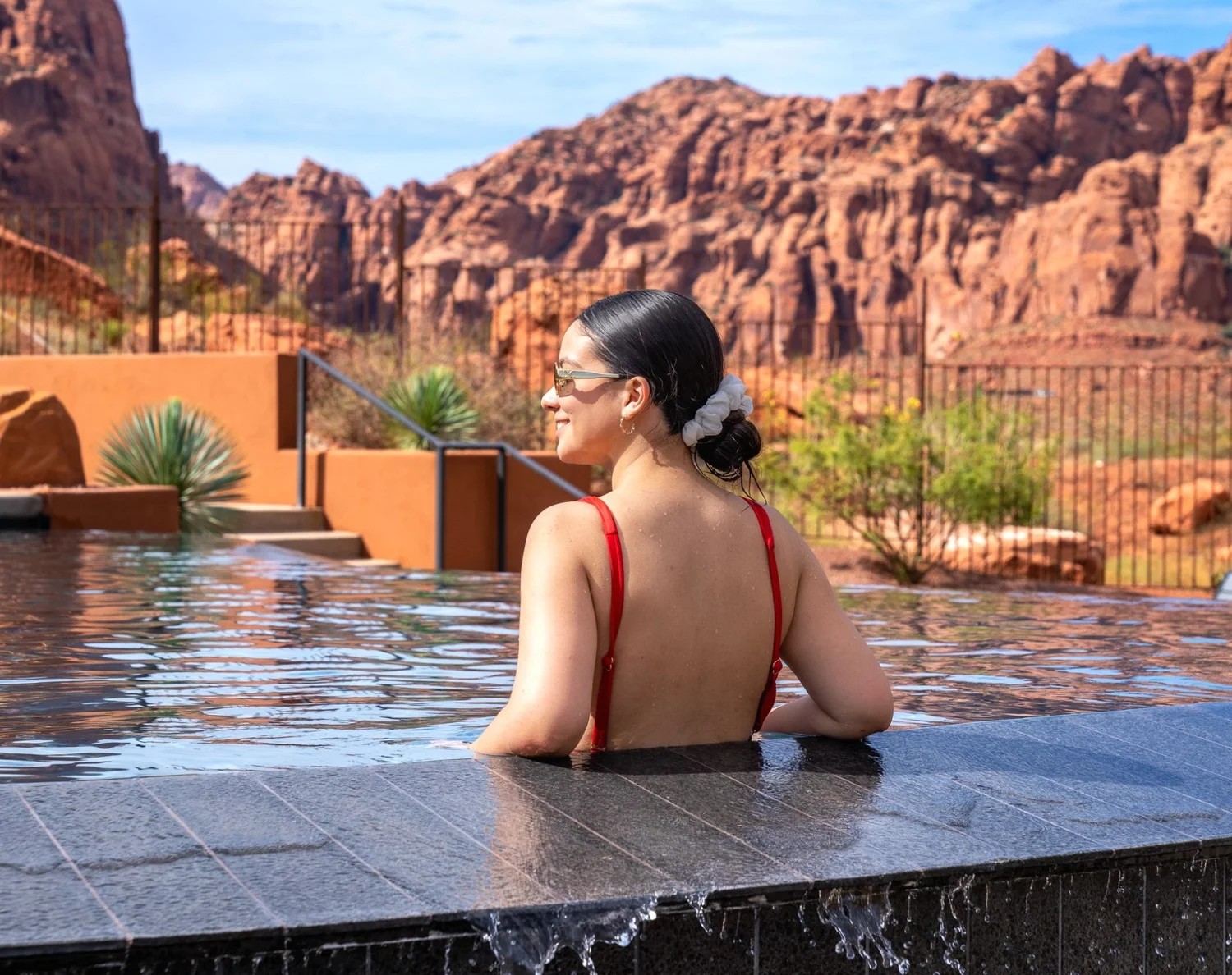 A guest enjoying a desert pool surrounded by red rock scenery.
