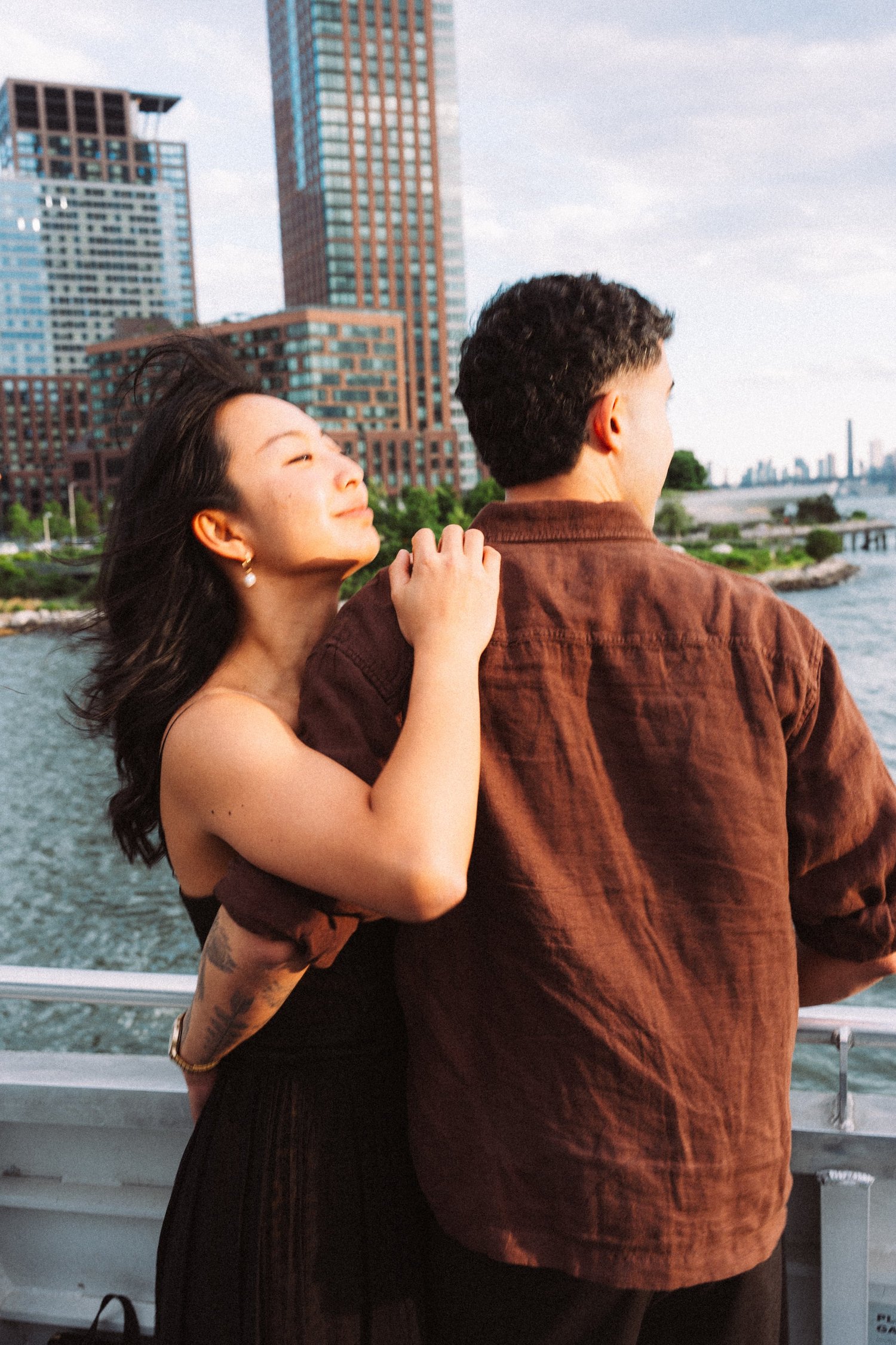Sophia embracing Mike outdoors with the New York skyline behind them