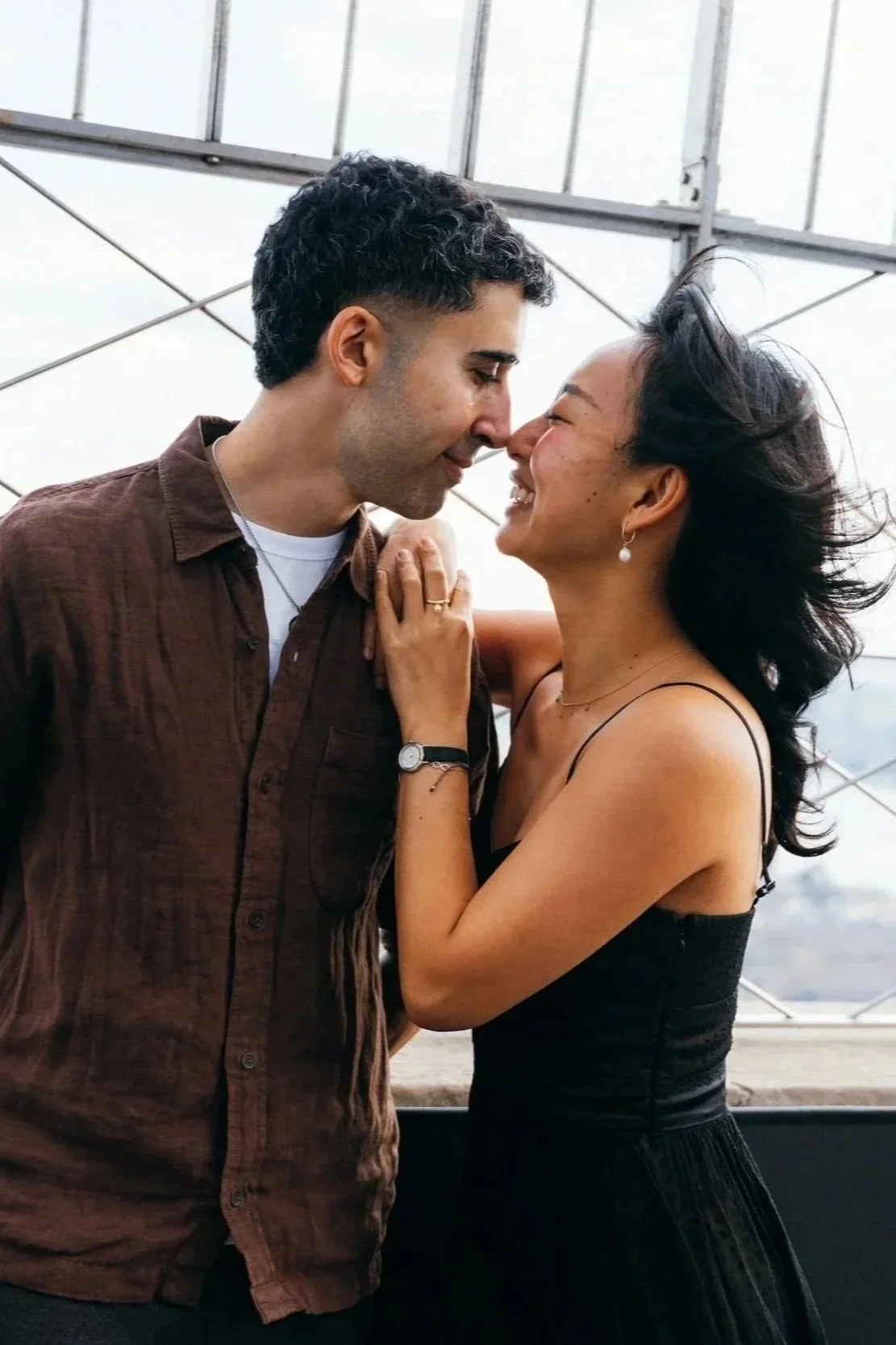 Couples photography: two people smiling together on a city observation deck.