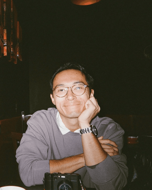 Zian Meng smiling at a table with a camera in front of him