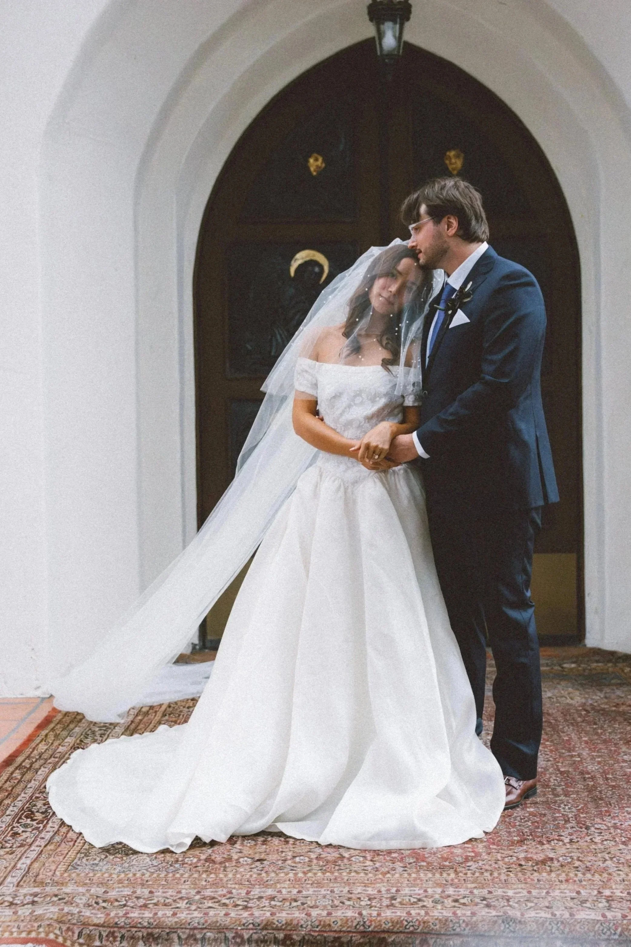 Wedding photography: newlyweds embracing beneath an arched church doorway.