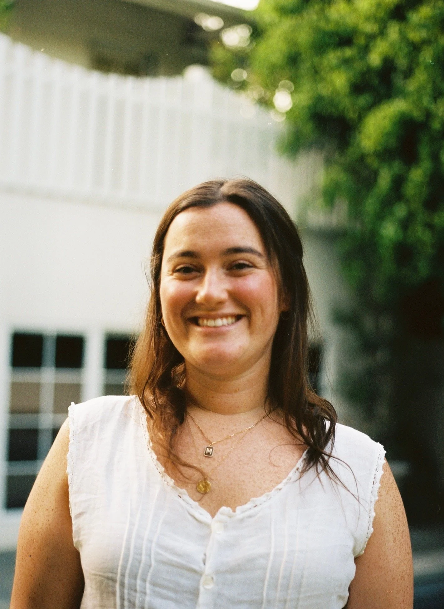Person sitting on a leather chair, wearing a beige sweater and black pants, with a potted plant in the background.