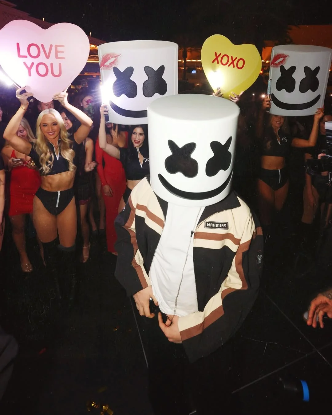 Marshmello walking up to booth with XS Servers holding signs that say XOXO and Love you.